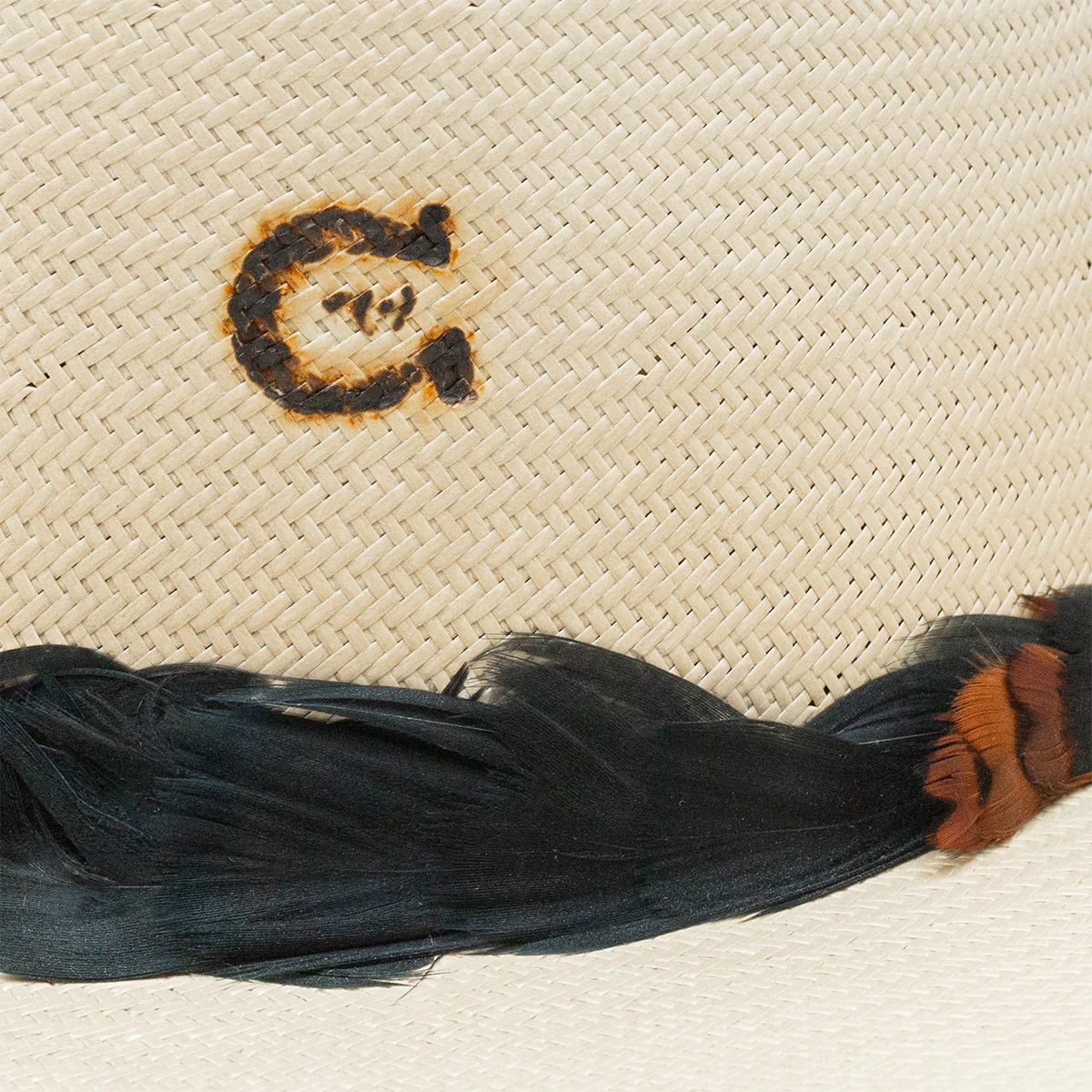 Straw hat detail with G logo and feathers