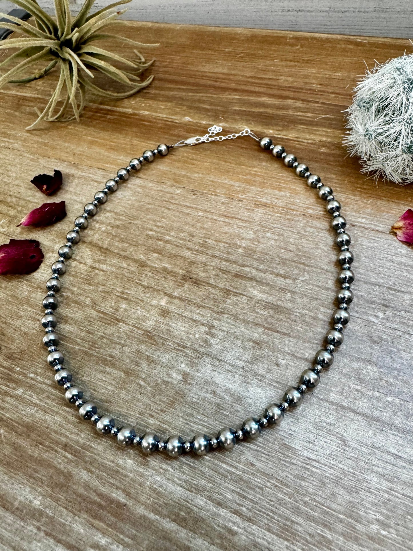 Silver bead necklace on wood