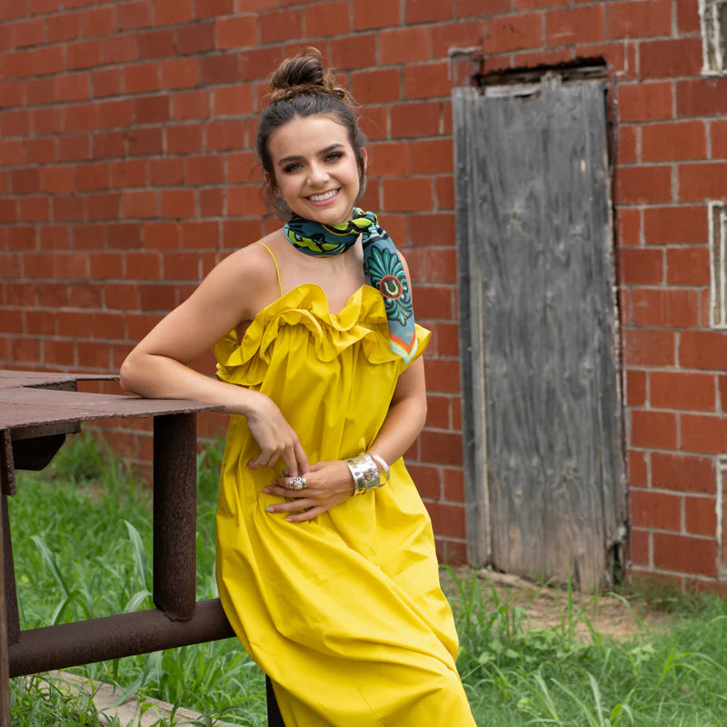 Woman in yellow dress by brick wall