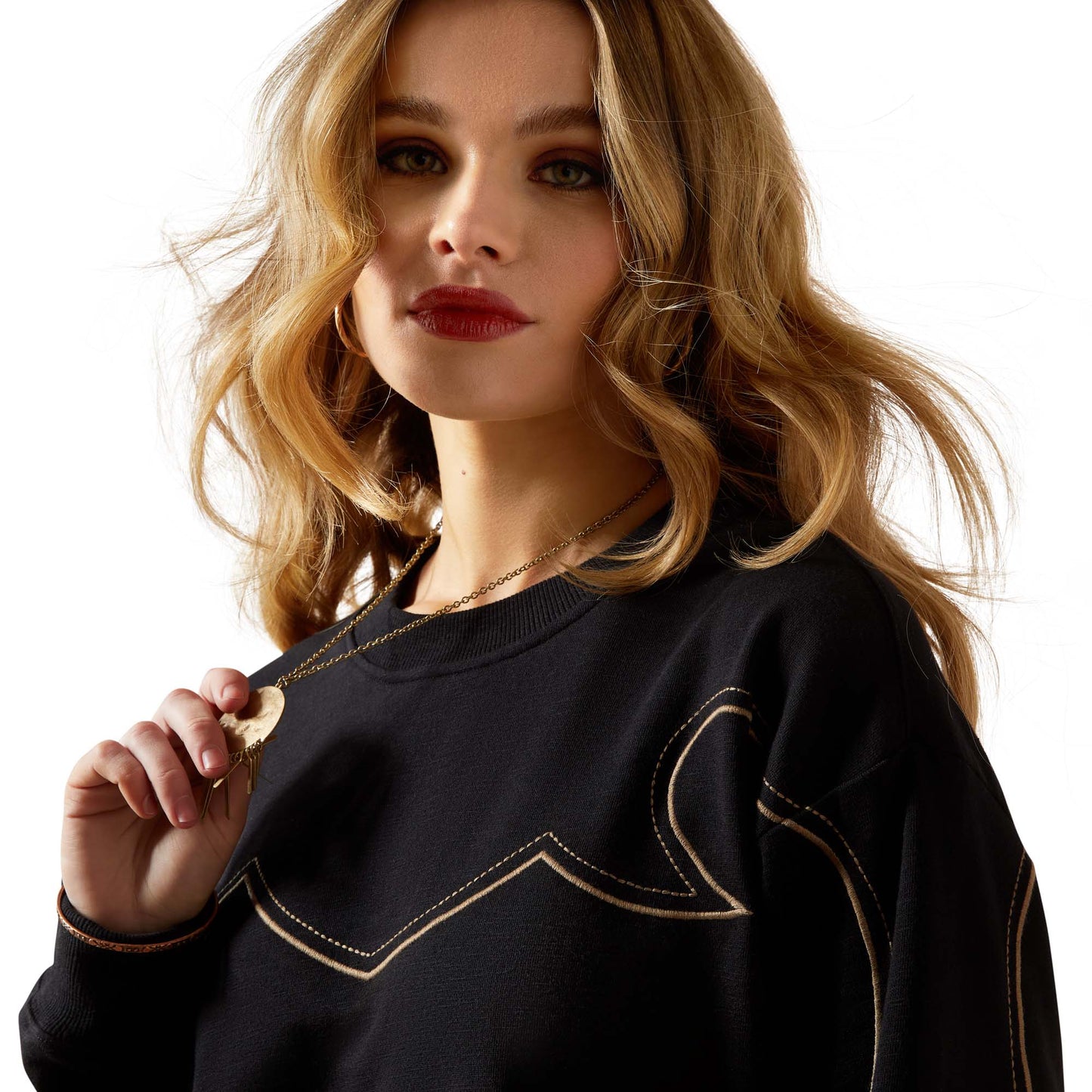 Woman in black sweatshirt with gold detail, F25_WMS_WEST