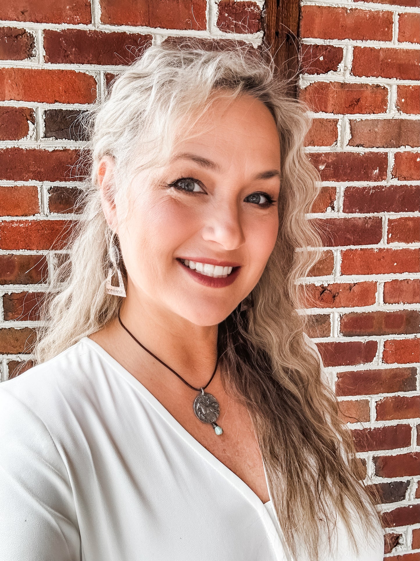 Woman smiling, Facetune photo 08-01-2024 against brick wall.