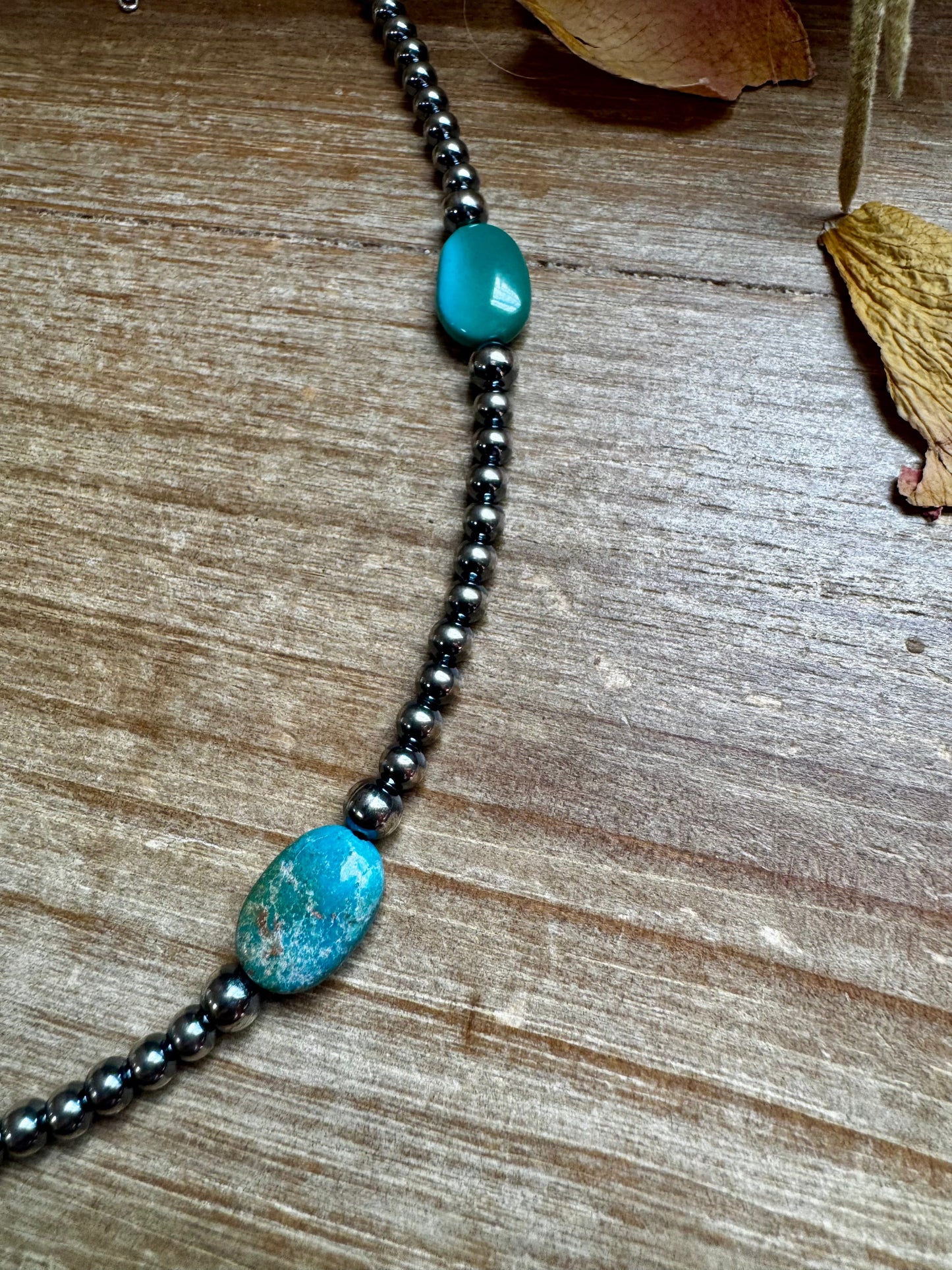 Turquoise and hematite bead necklace on wood