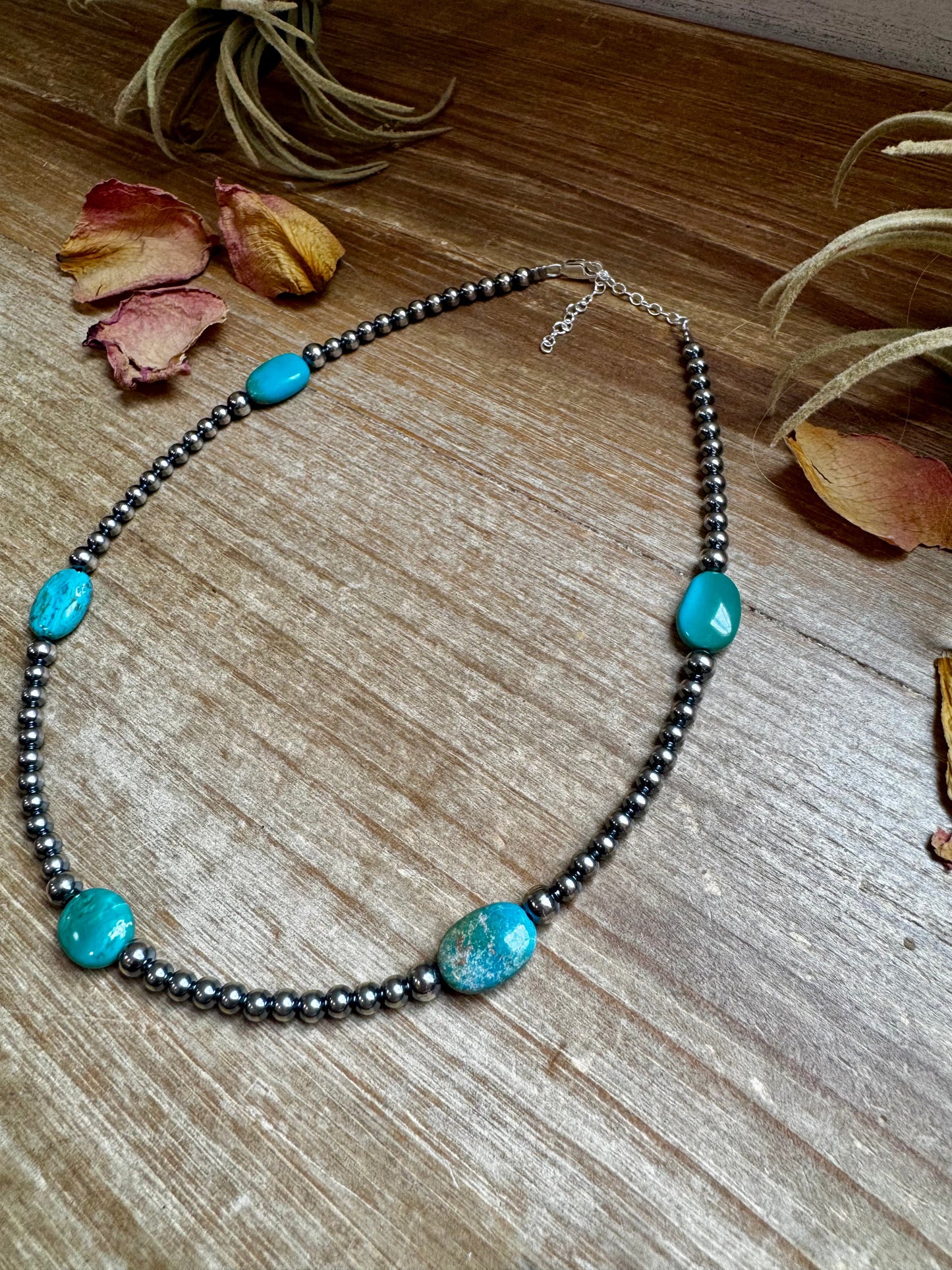 Turquoise bead necklace on wood surface