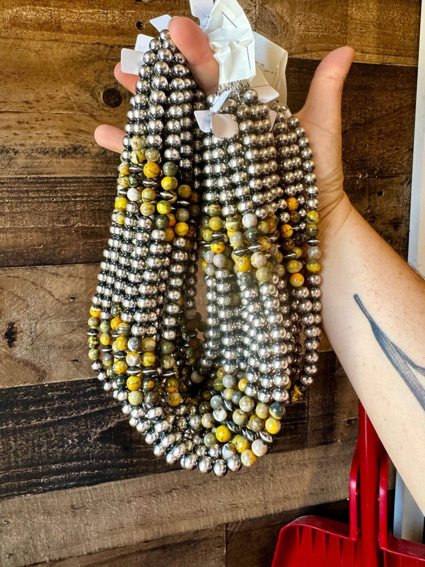 Hand holding beaded necklace with yellow accents