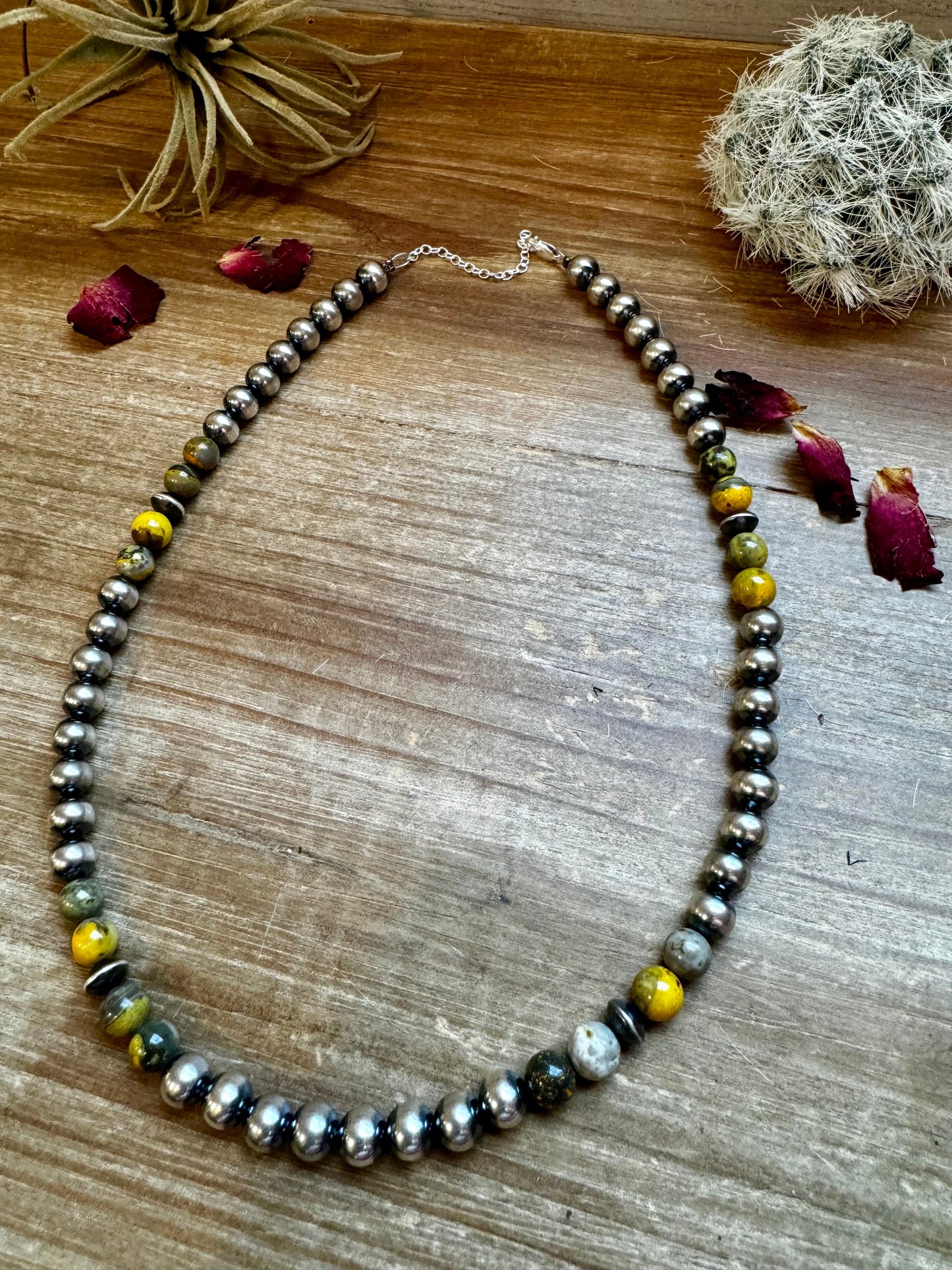 Silver and gemstone bead necklace on wood surface