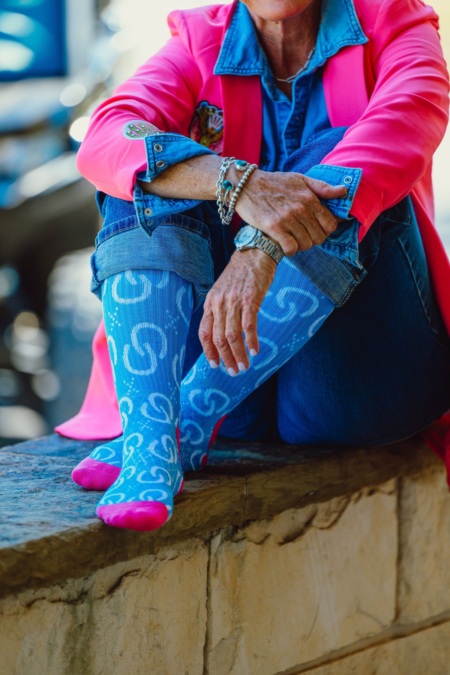 Woman in pink blazer and blue jeans with patterned socks