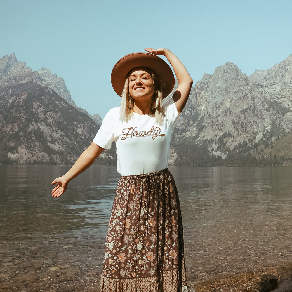 Woman in Howdy tee near mountains