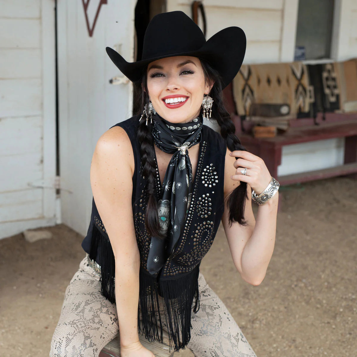 Cowgirl wearing black wild rag scarf and concho, smiling.
