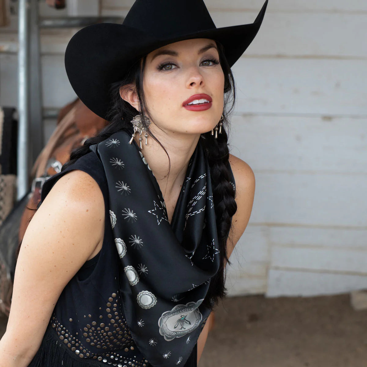 Cowgirl in black hat and silk scarf with concho design.