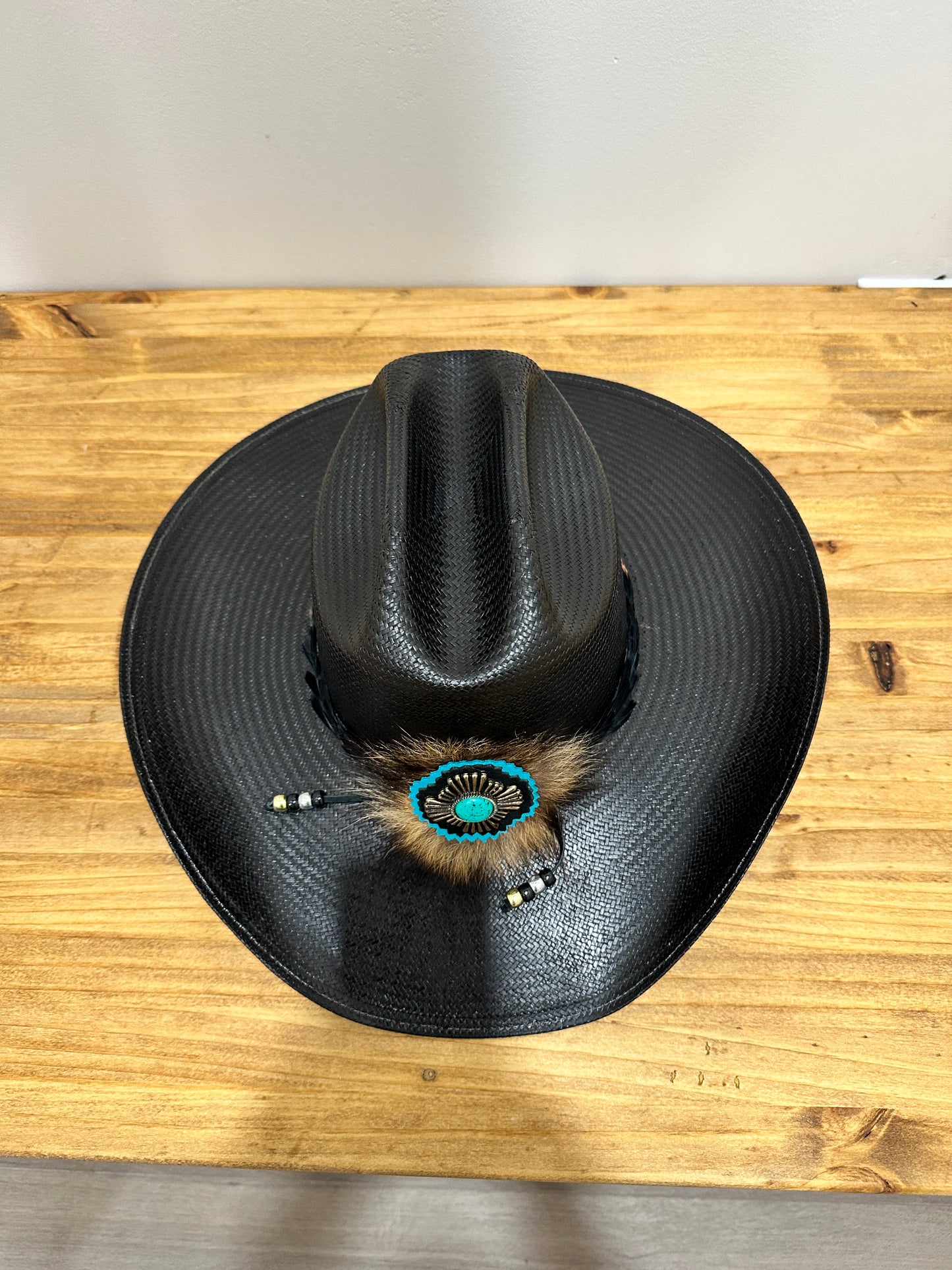 Black cowboy hat with turquoise and feather decoration.