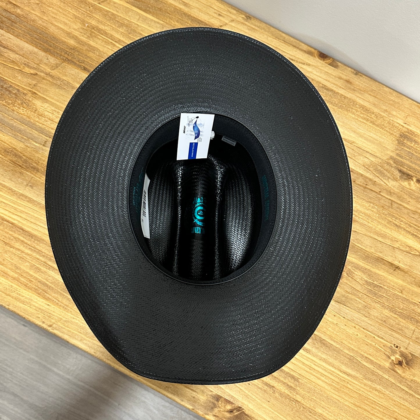 Top-down view of a black cowboy hat on a wooden surface.