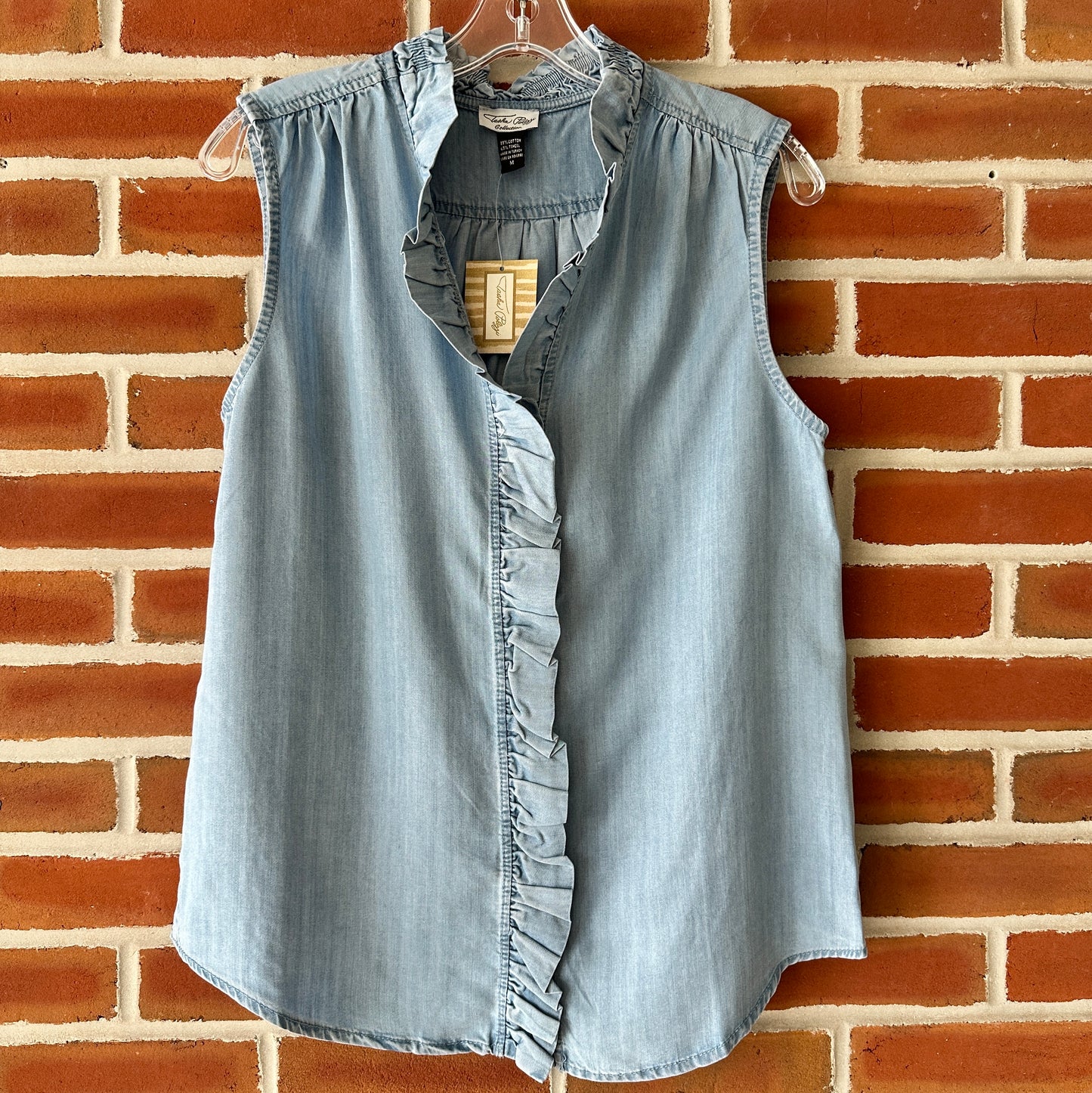 Blue denim sleeveless top with ruffle detail.