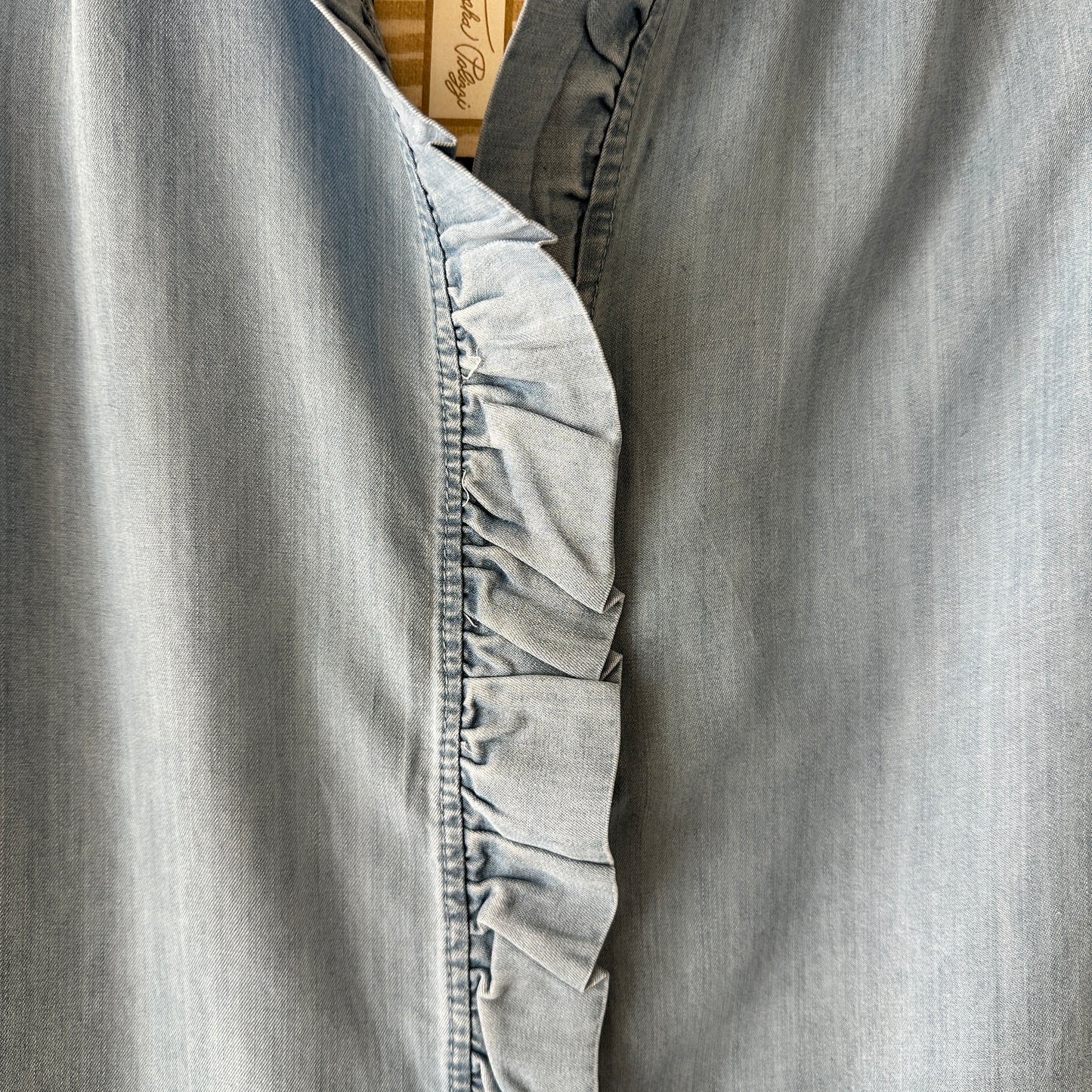 Close-up of a denim shirt with ruffle detail.