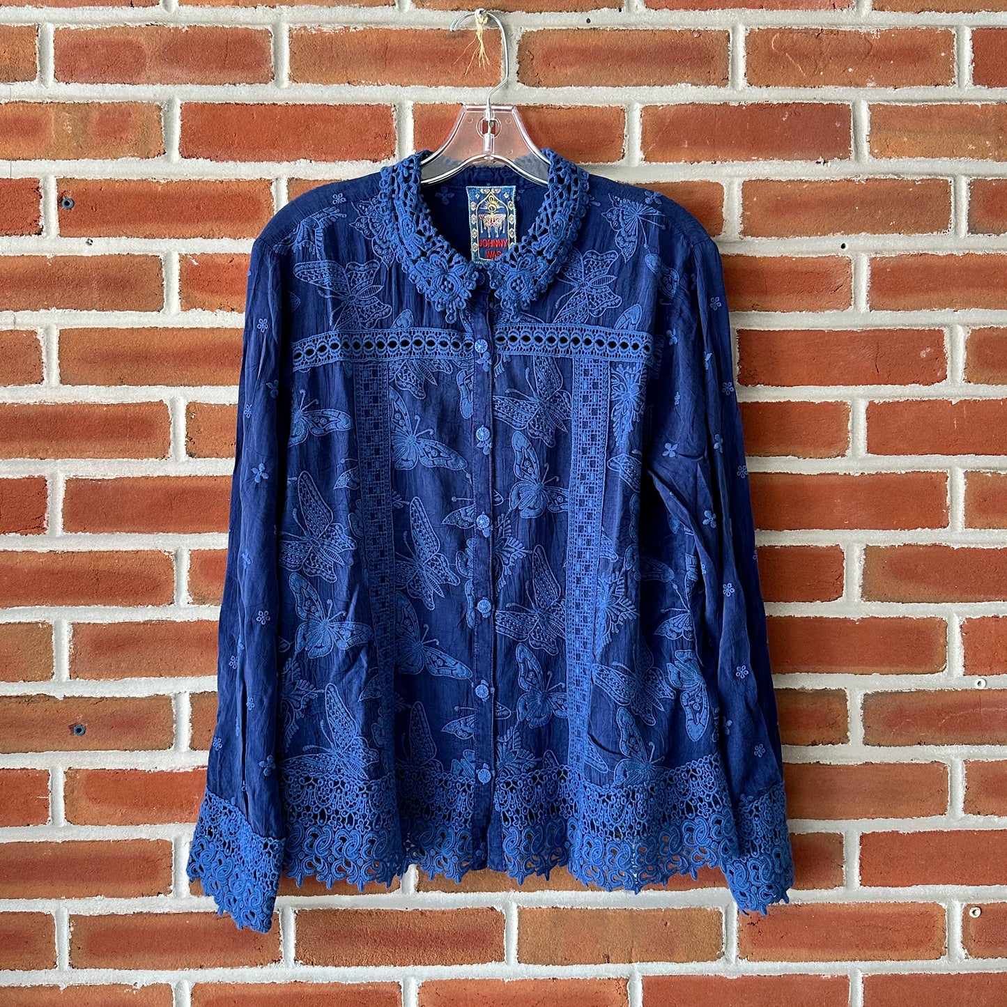 Blue embroidered button-up shirt hanging on a hanger.