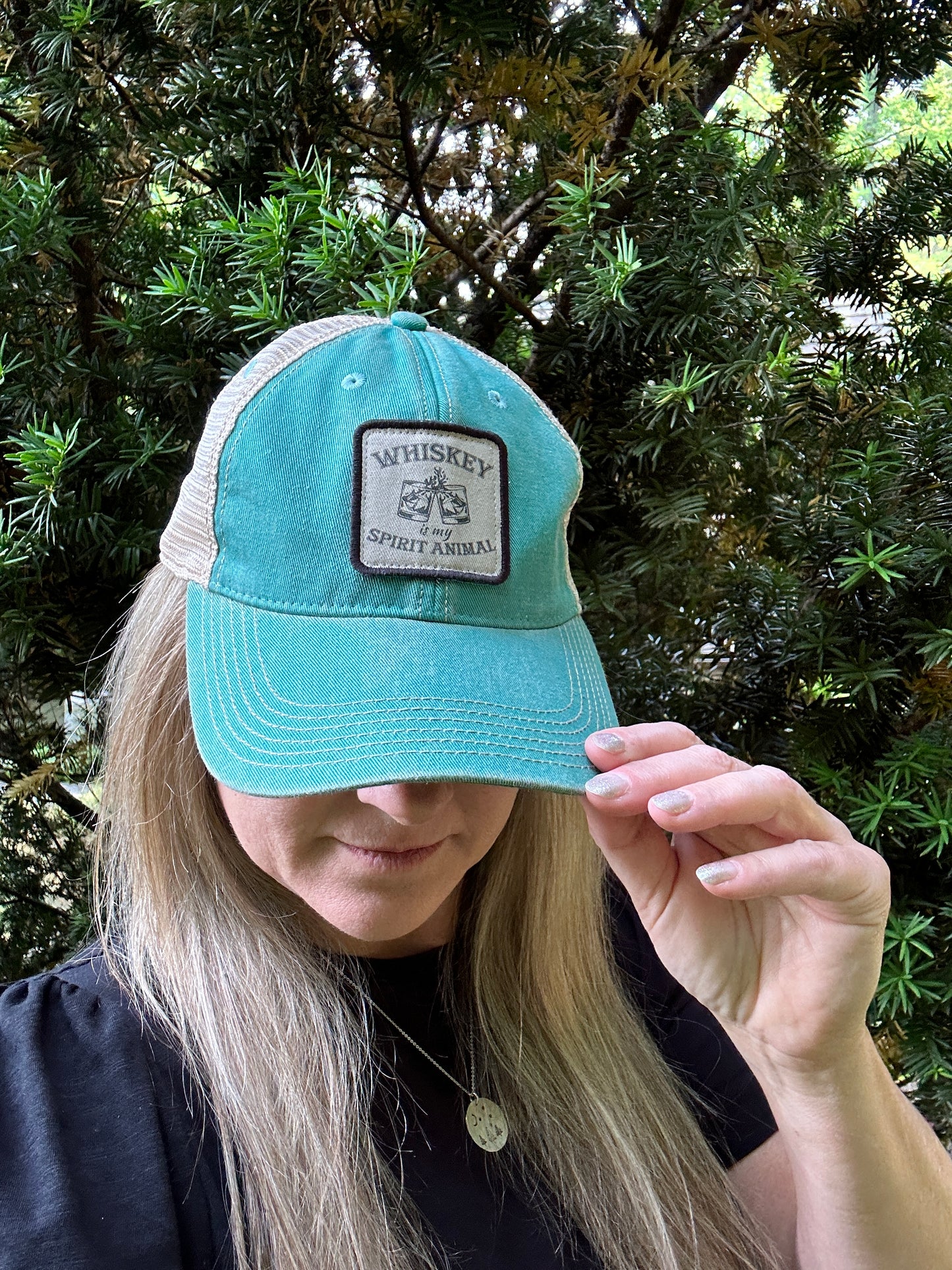 Woman wearing a teal baseball cap with a patch.