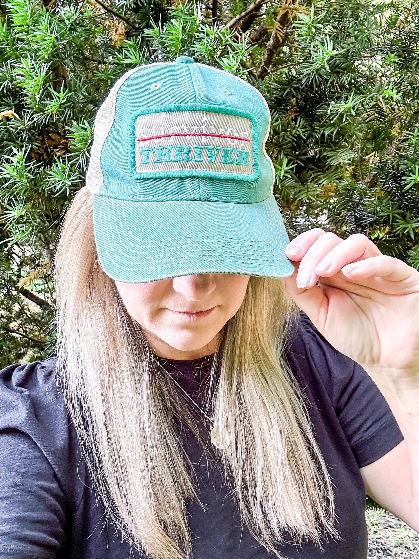 Woman wearing a teal Survivor or Thriver hat.
