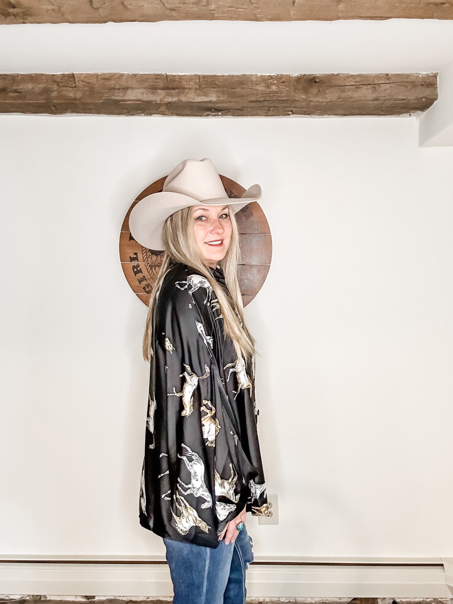 Woman in cowboy hat and patterned shirt smiling.