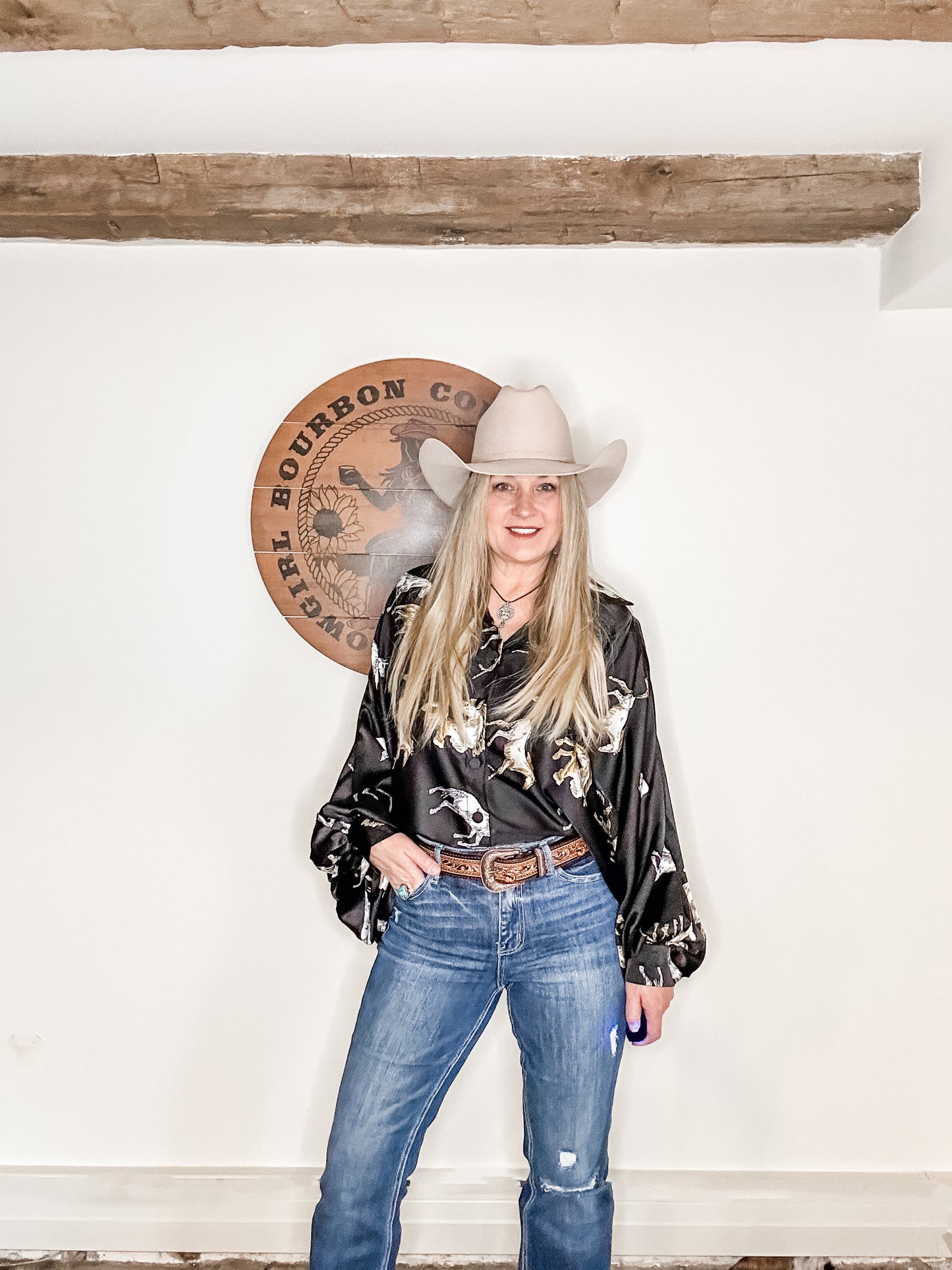 Woman in cowboy hat and shirt, jeans.