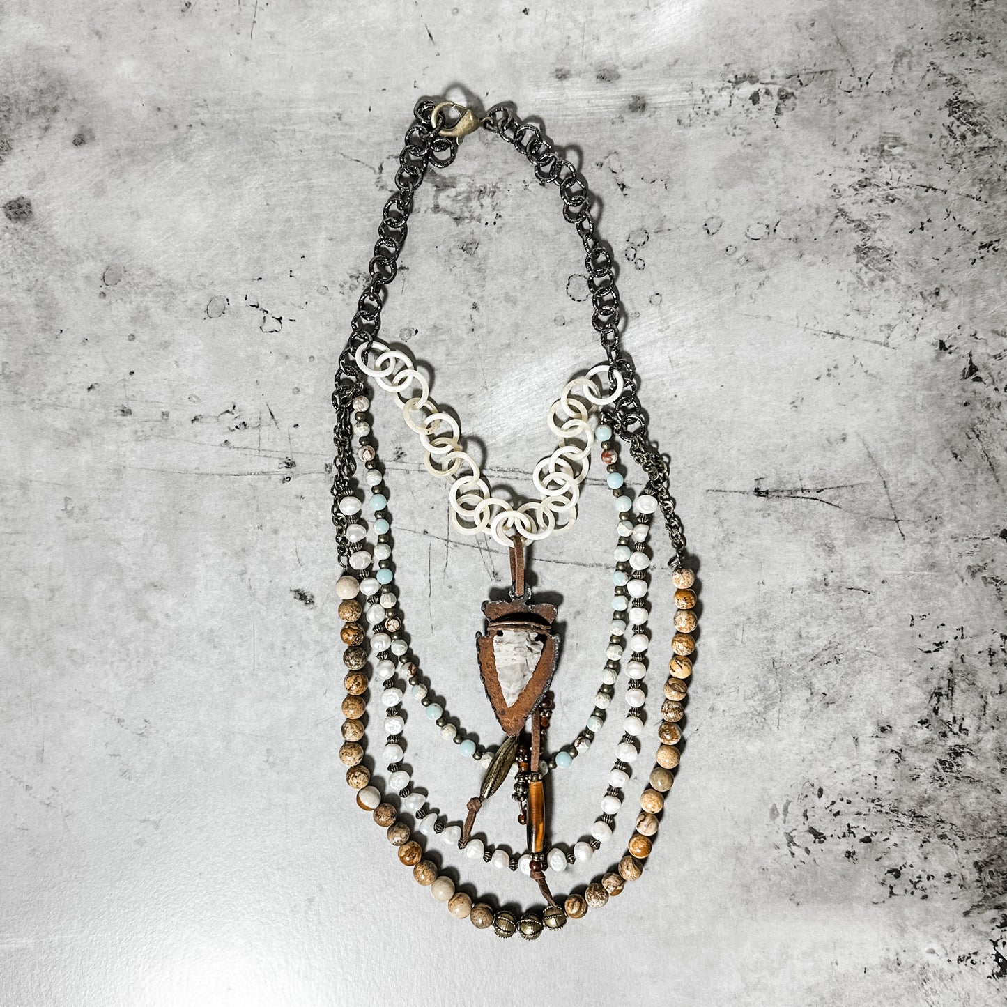 Layered statement necklace on a gray surface.