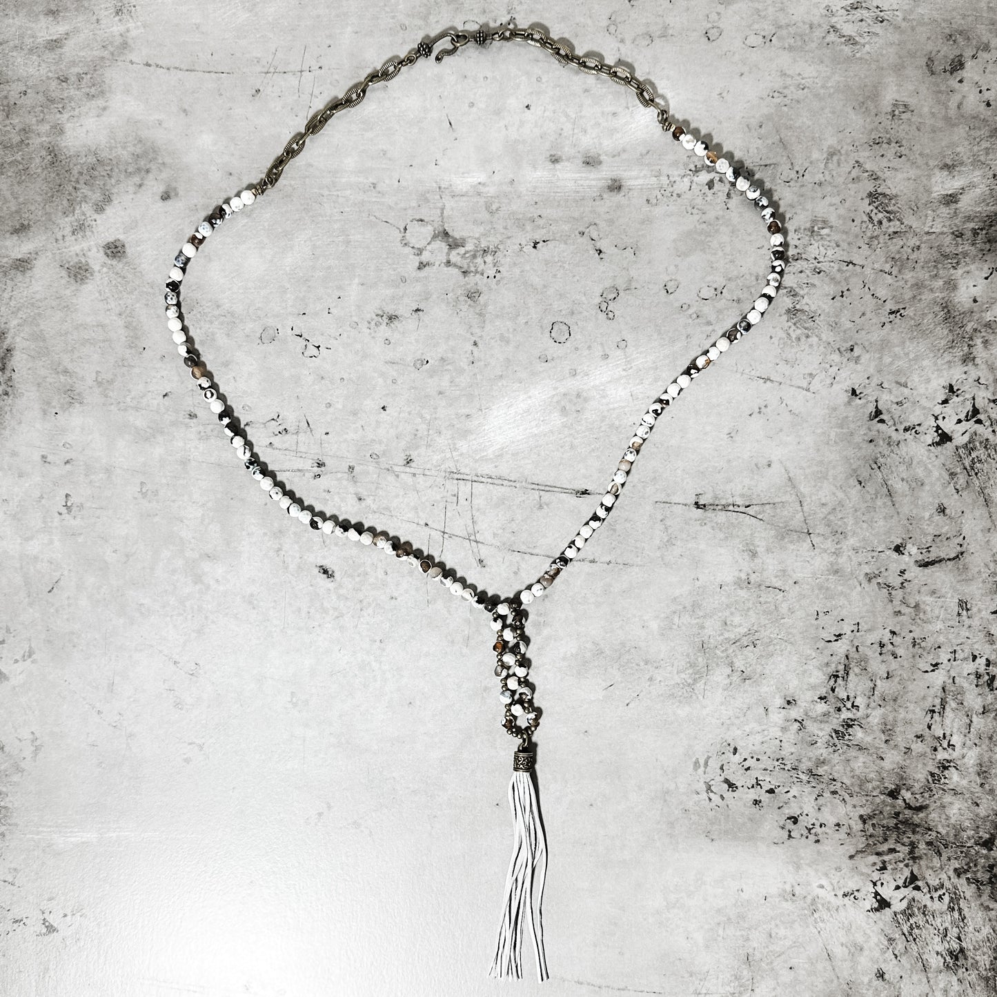 Necklace with white beads and tassel.