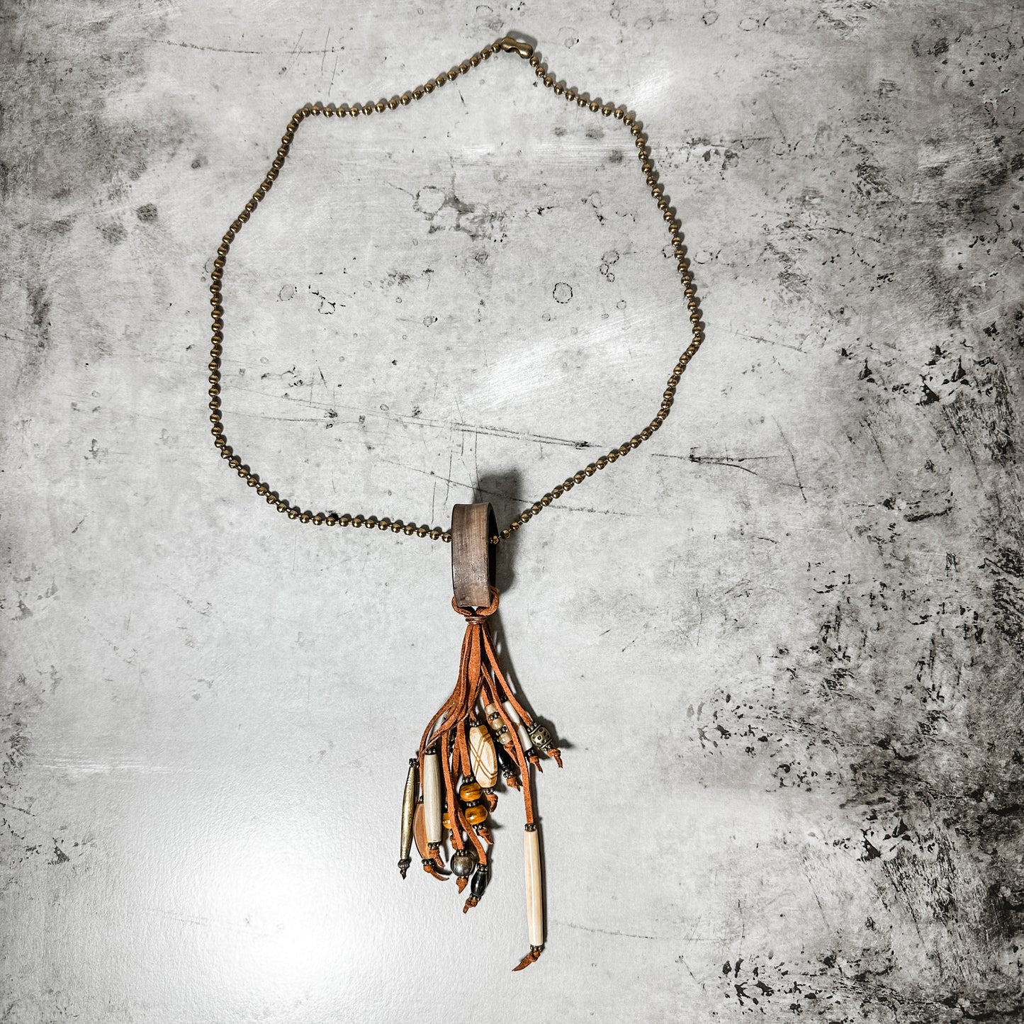 Necklace with leather and beads on a textured surface.