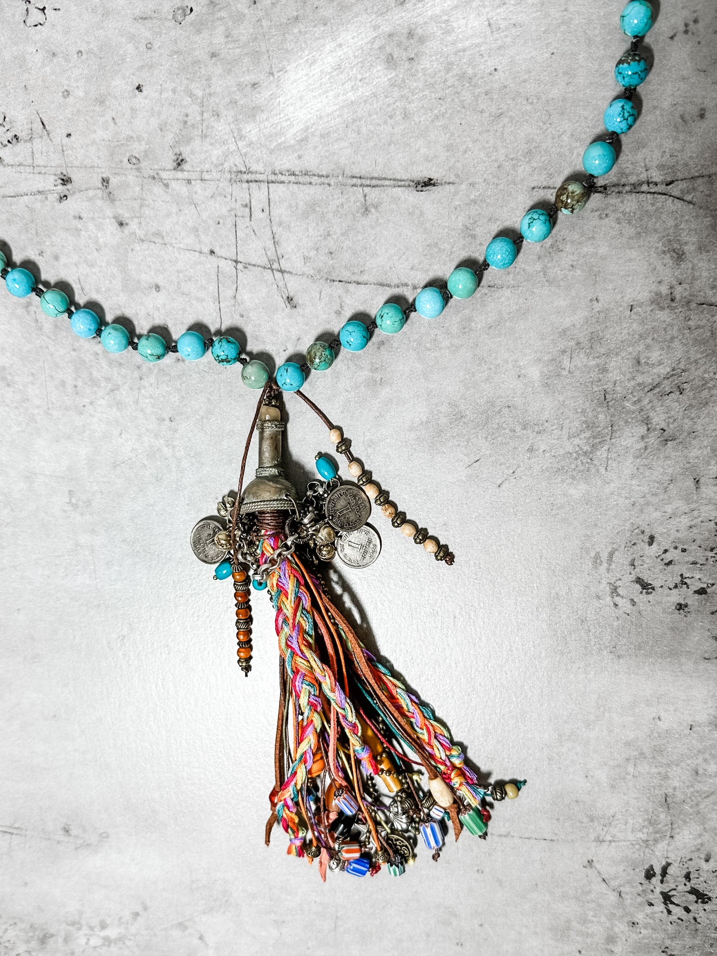 Turquoise bead necklace with a colorful tassel pendant.
