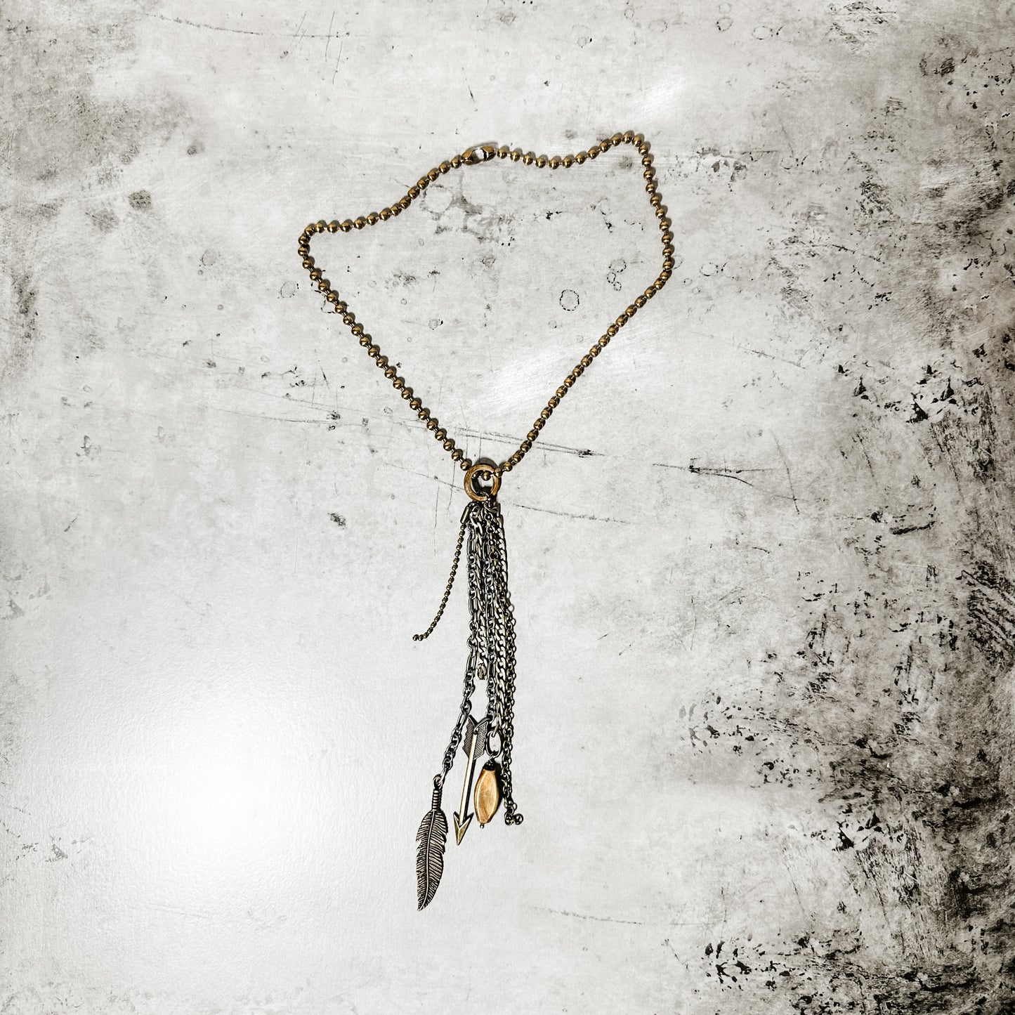 Necklace with dangling chains and feather.