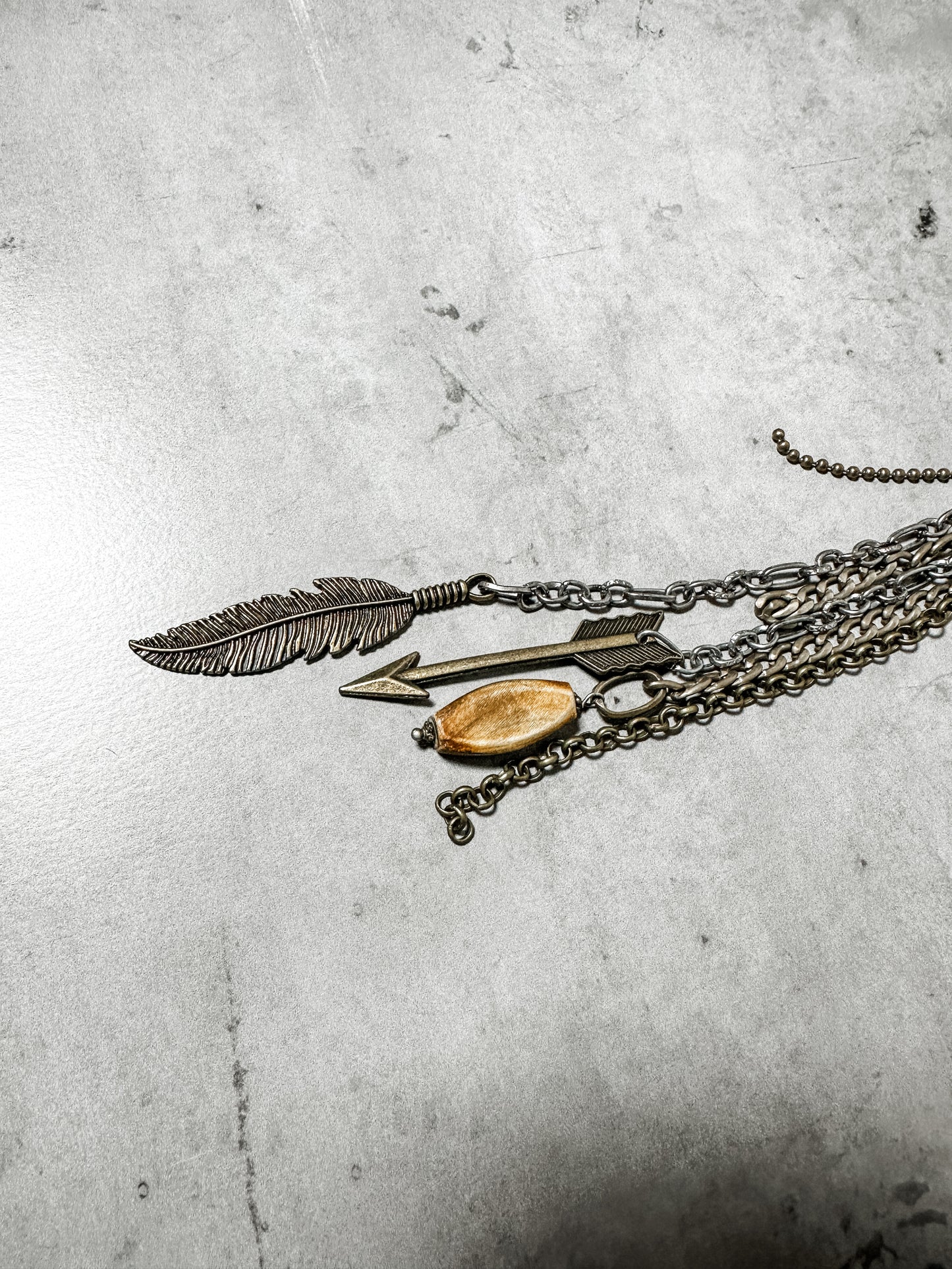 Necklace with feather, arrow, and bead pendants.