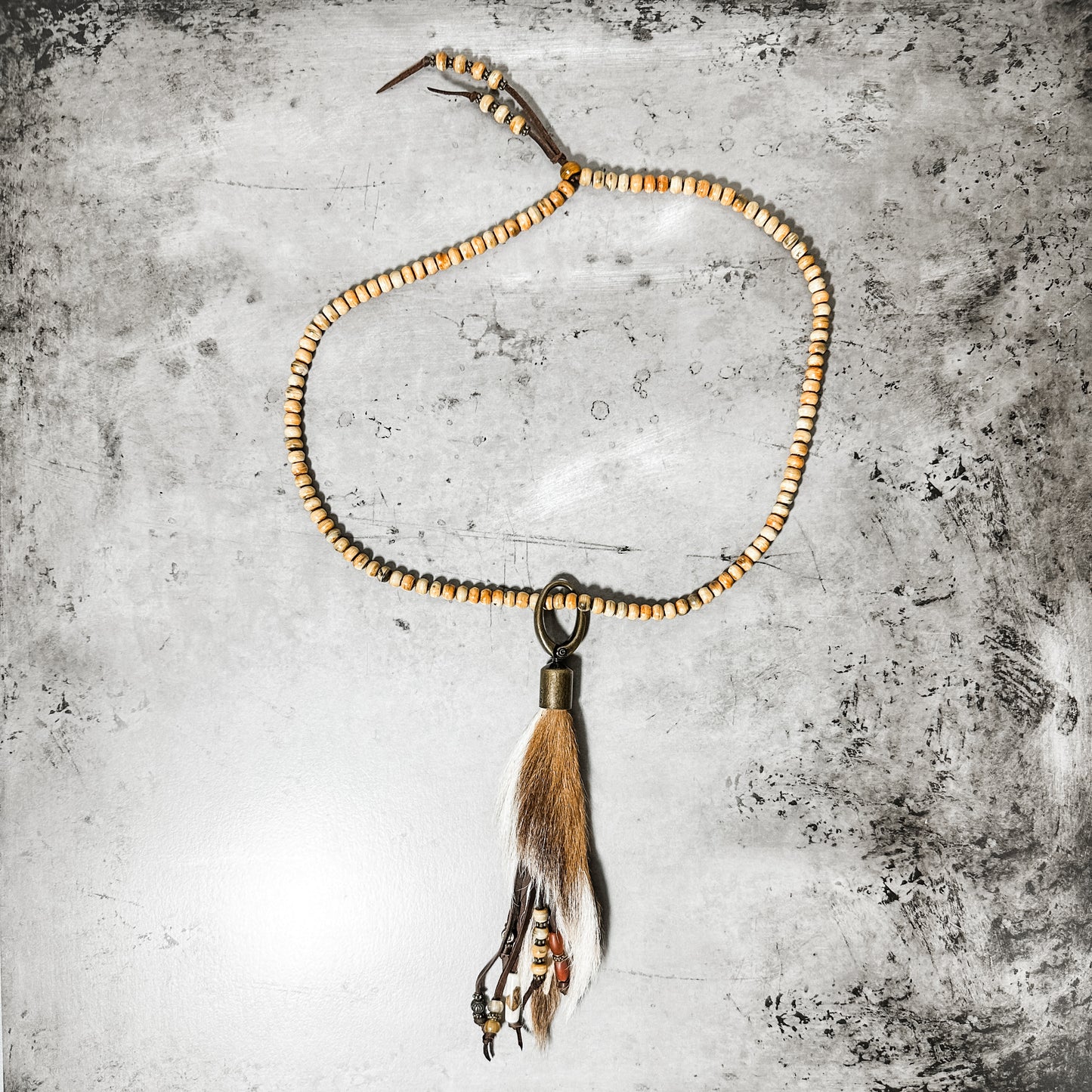 Necklace with beaded chain and feather pendant.