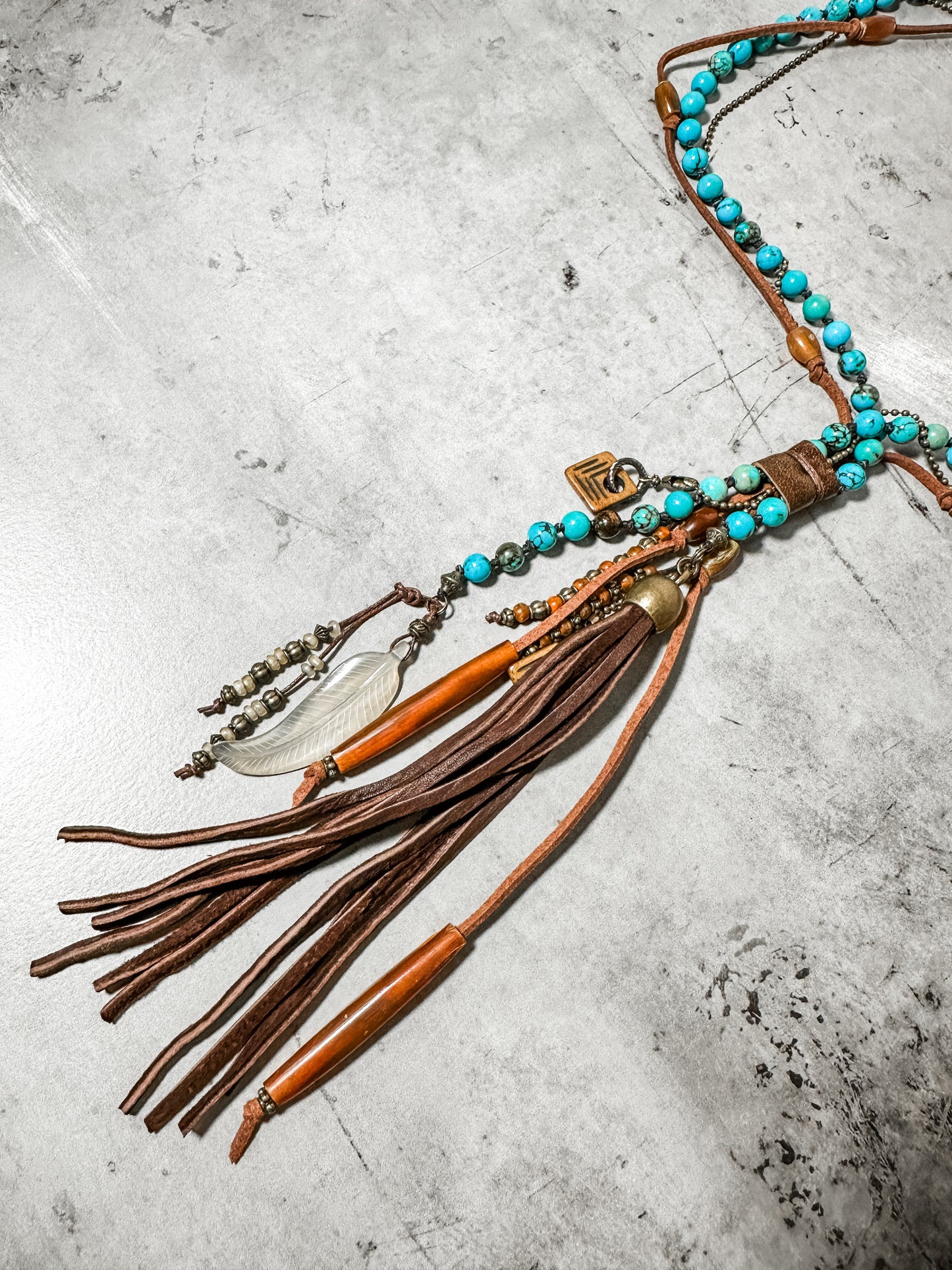 Necklace with turquoise beads and leather tassels.