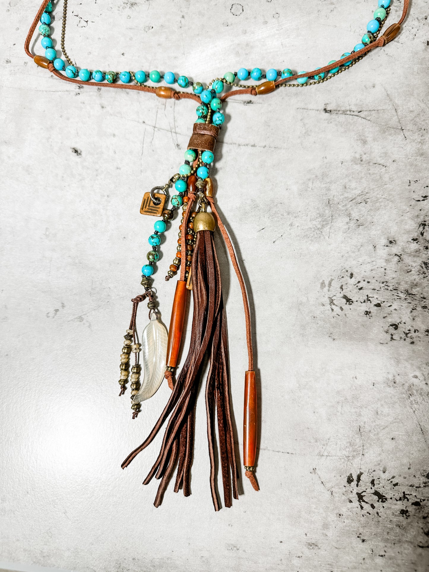 Turquoise beaded necklace with leather tassel pendant.