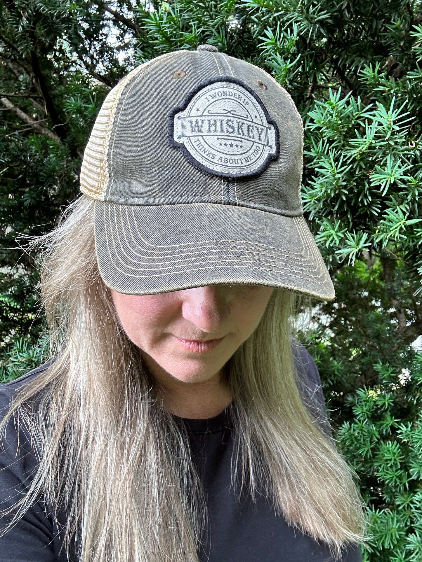 Woman wearing a green and tan whiskey hat.
