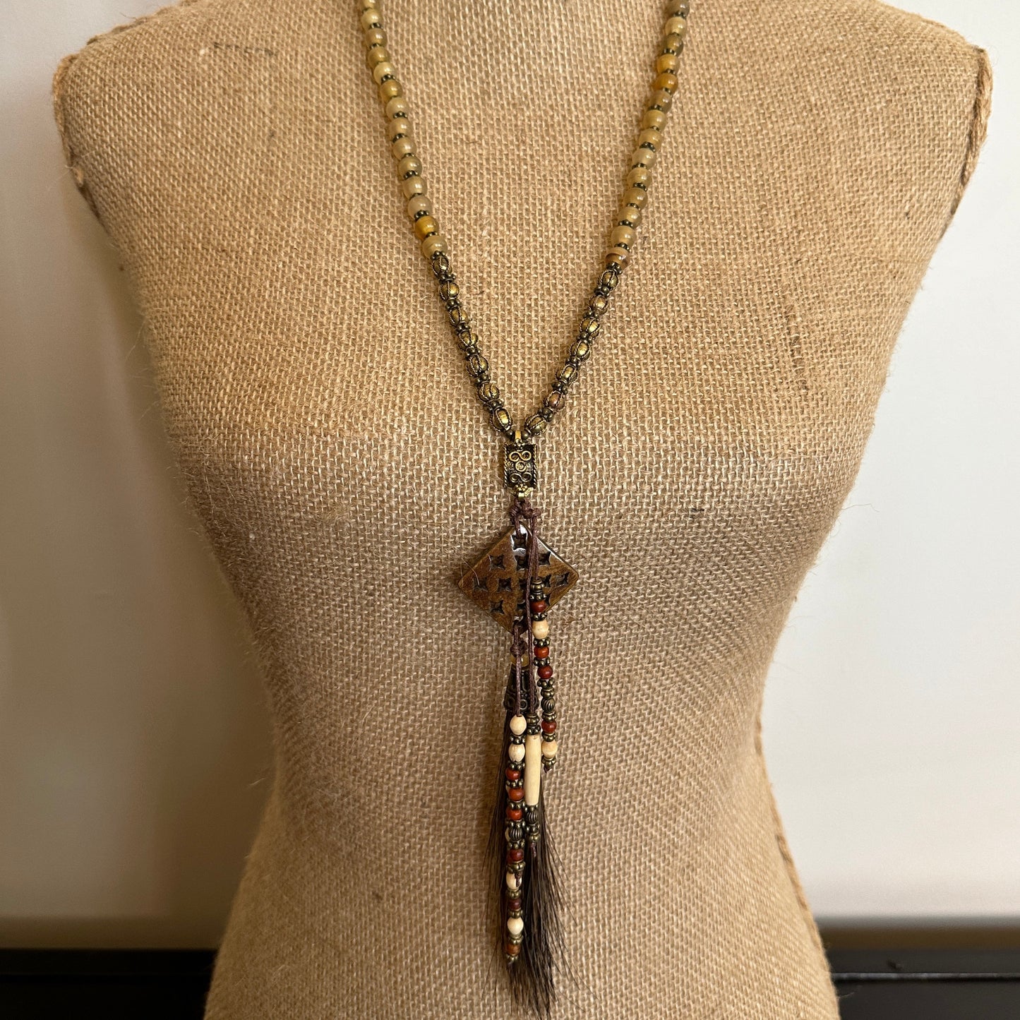 Beaded necklace with pendant on mannequin.