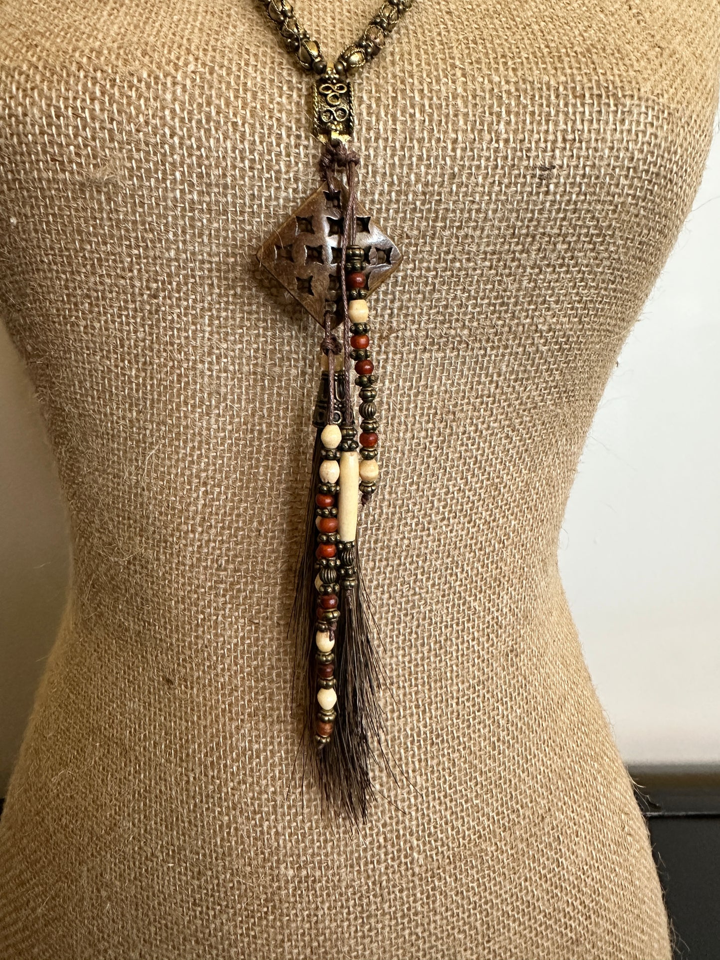 Necklace with a decorative pendant and beads on a mannequin.