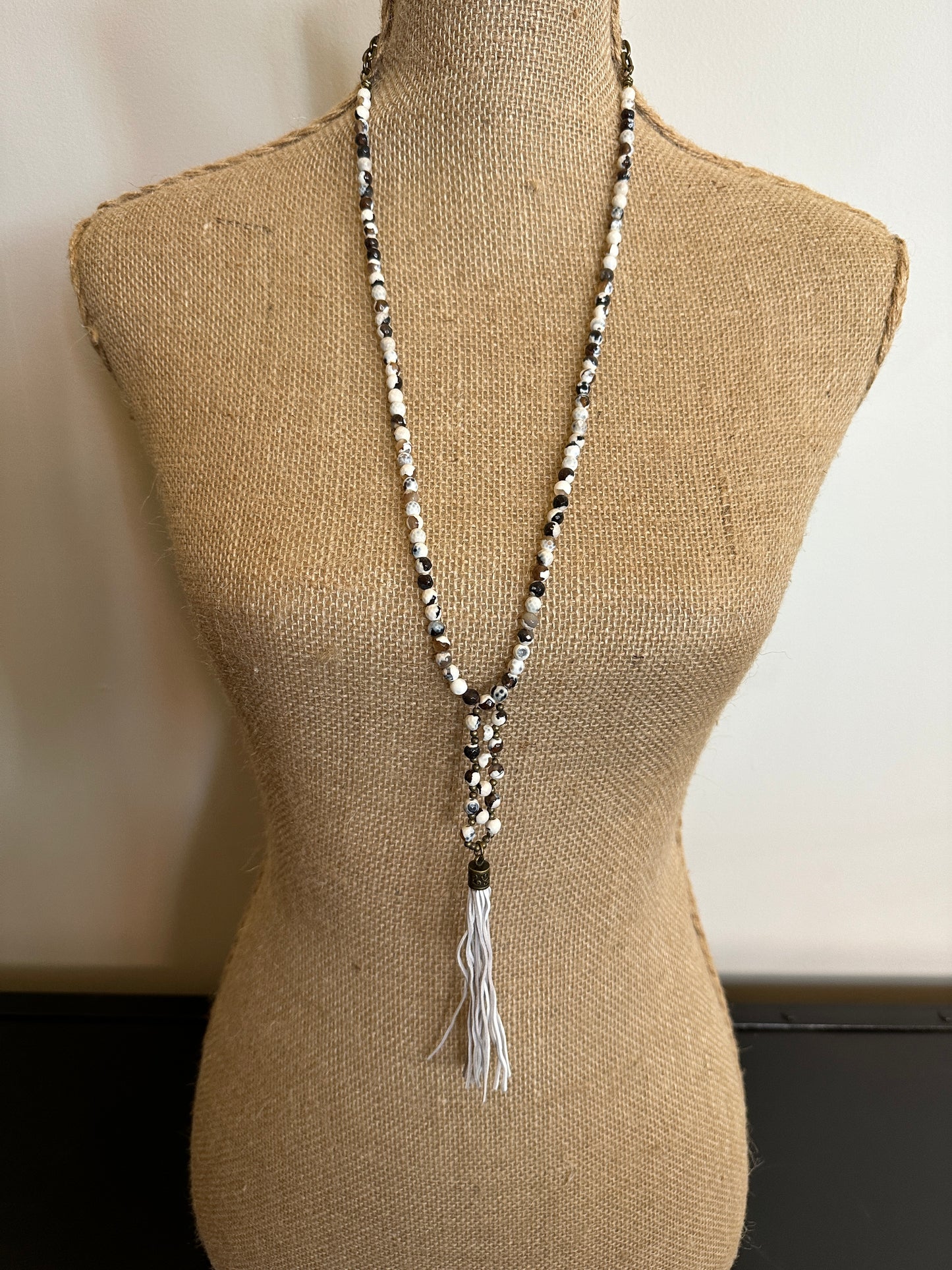 Beaded necklace on a mannequin with a tassel.