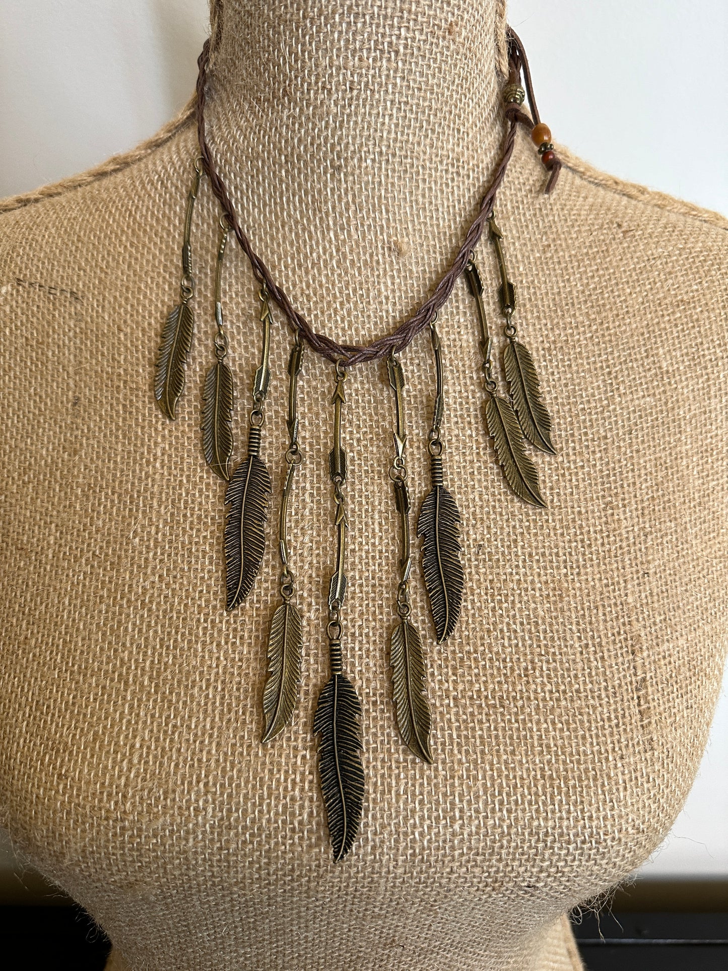 Necklace with bronze feather pendants on a mannequin.