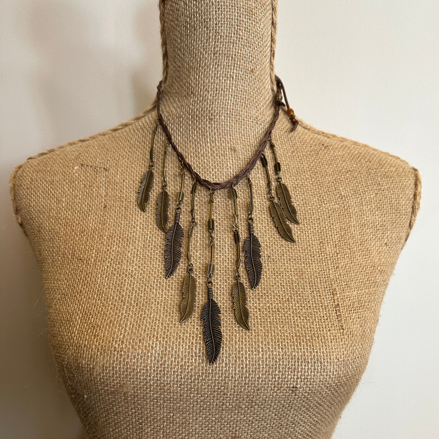 Feather pendant necklace on a mannequin.