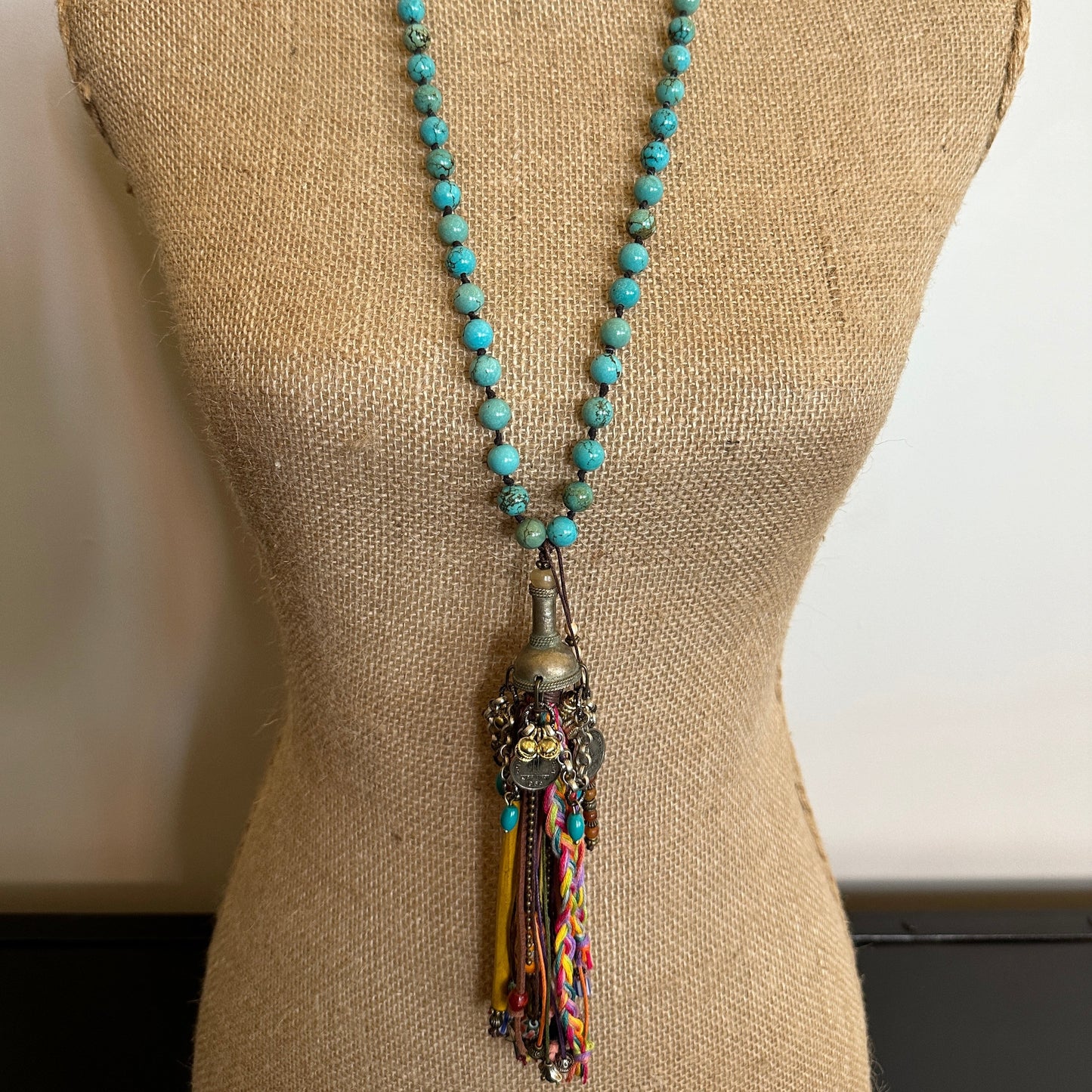 Turquoise beaded necklace with tassel detail on mannequin
