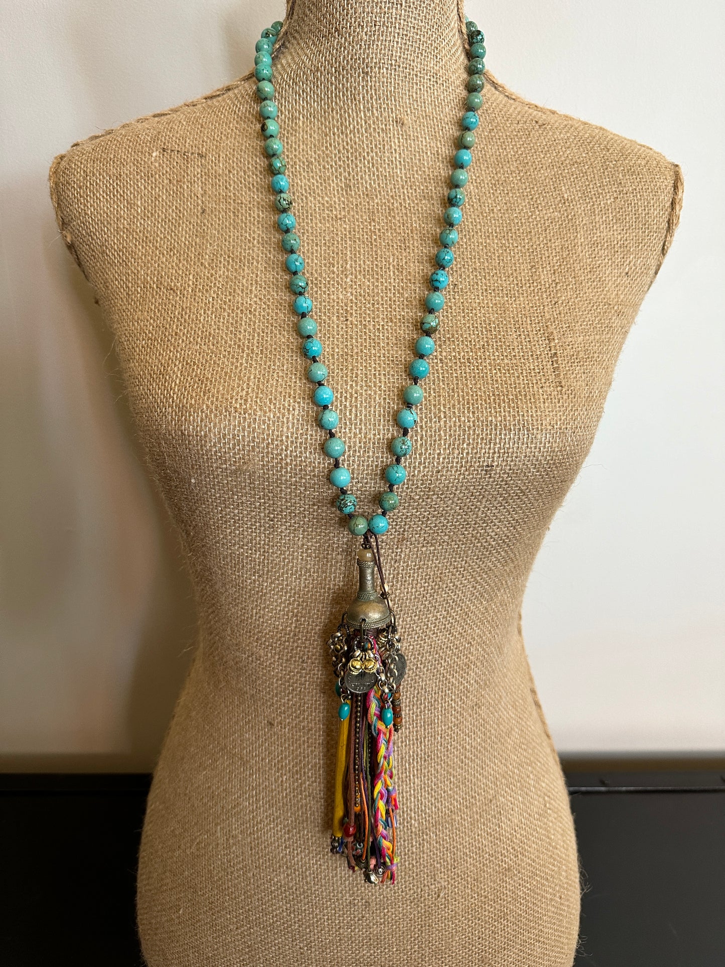 Turquoise beaded necklace with tassel on mannequin