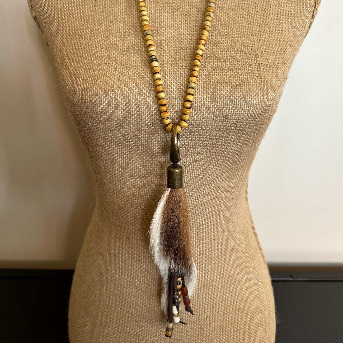 Beaded necklace with fur tassel on a mannequin.