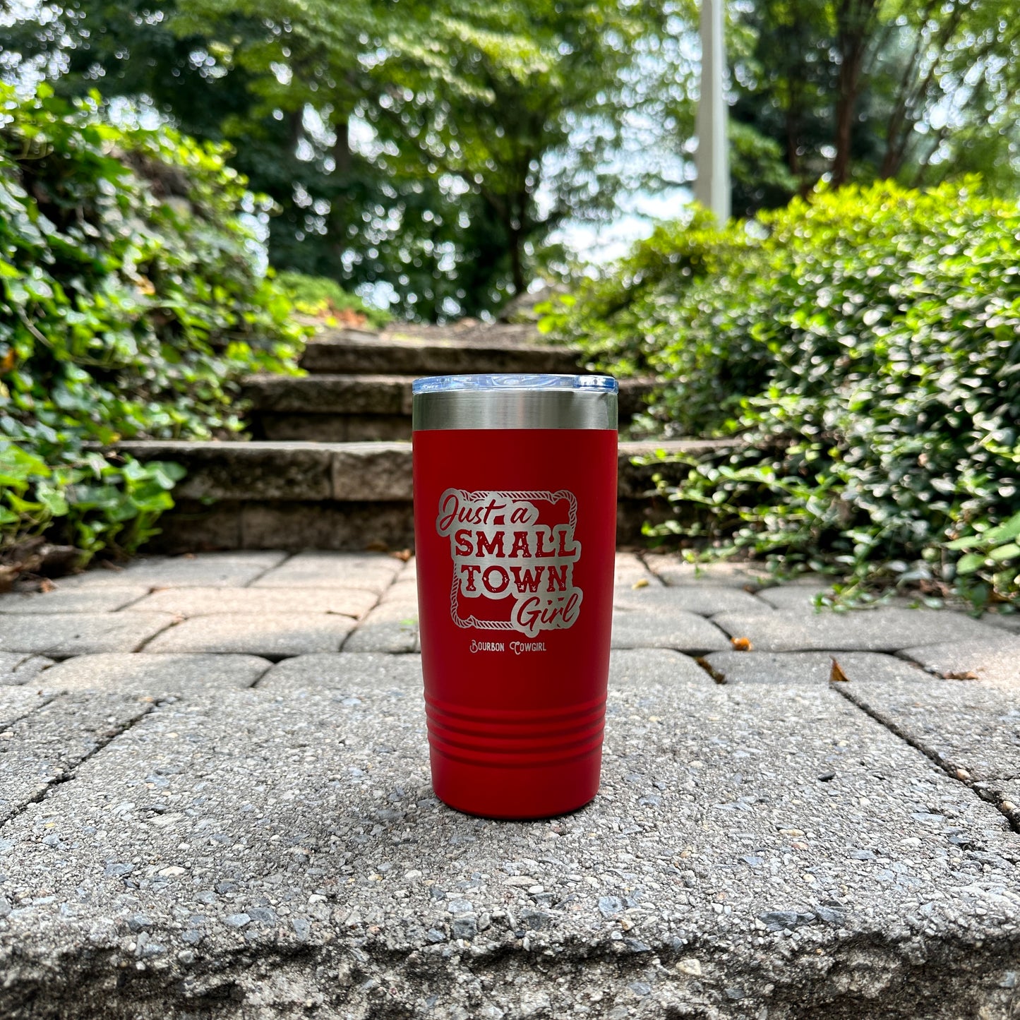 Red Just a Small Town Girl tumbler on a stone surface.