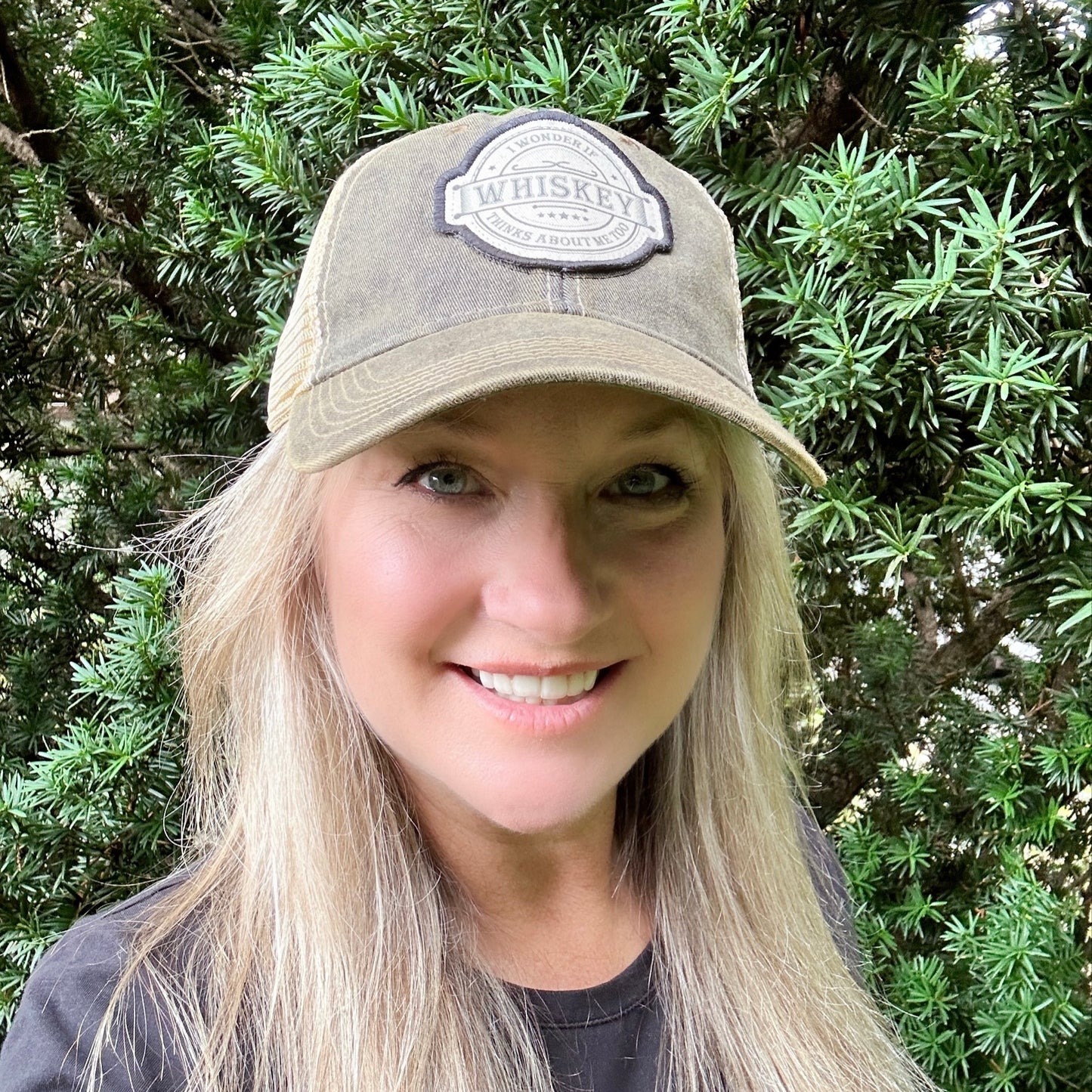 Woman wearing a whiskey hat, smiling.