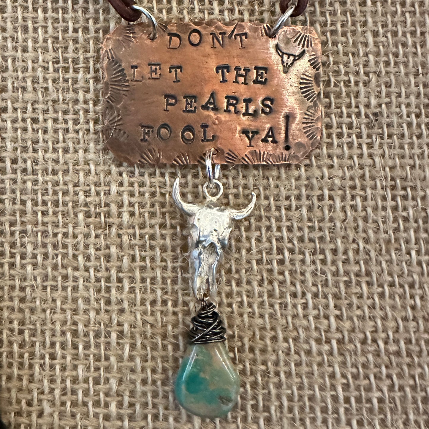 Copper pendant with a bull skull and turquoise stone.