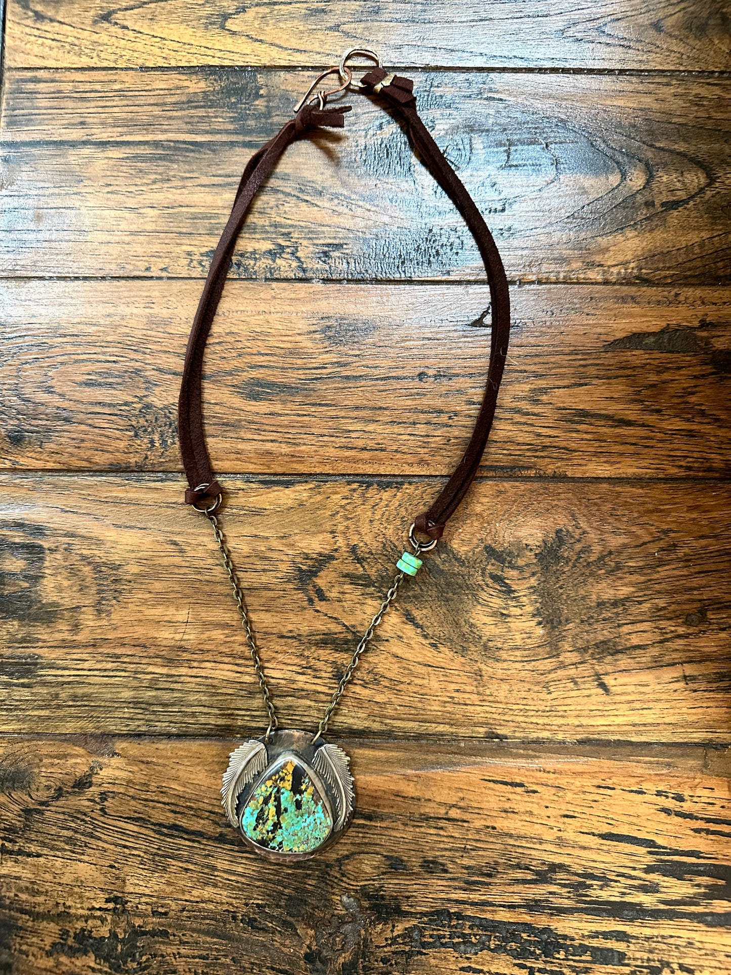 Necklace with turquoise stone on wood surface.