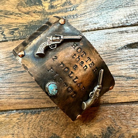 Copper cuff bracelet with gun embellishments.