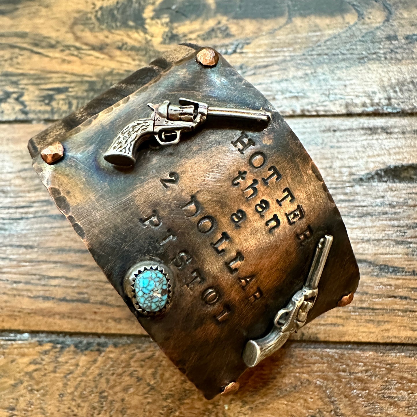 Copper plaque with pistol embellishments and text.