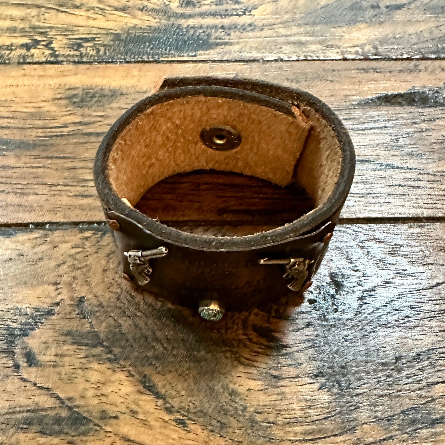 Brown leather wrist cuff with metal accents.