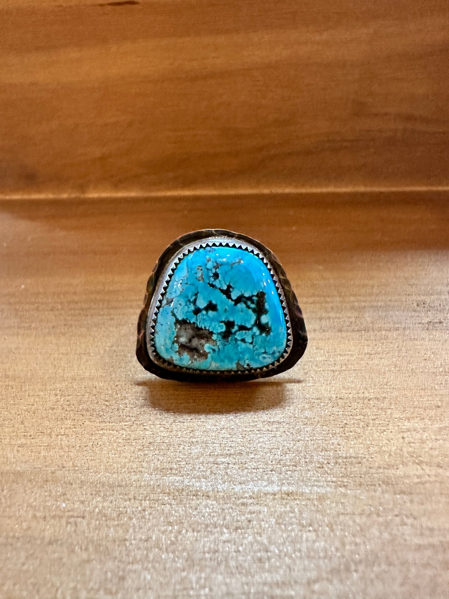 Turquoise stone ring on a wooden surface.