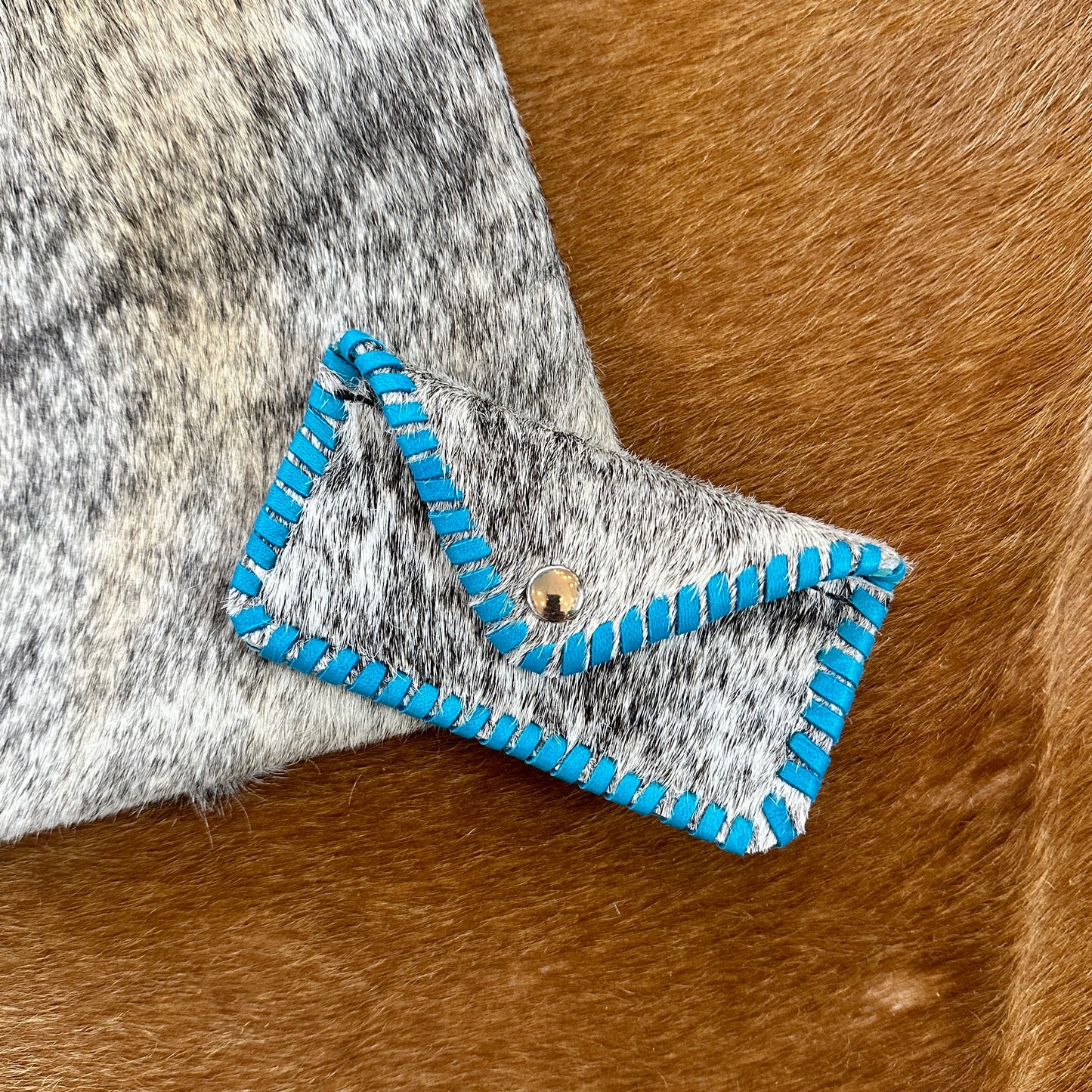 Small gray leather wallet with turquoise stitching.