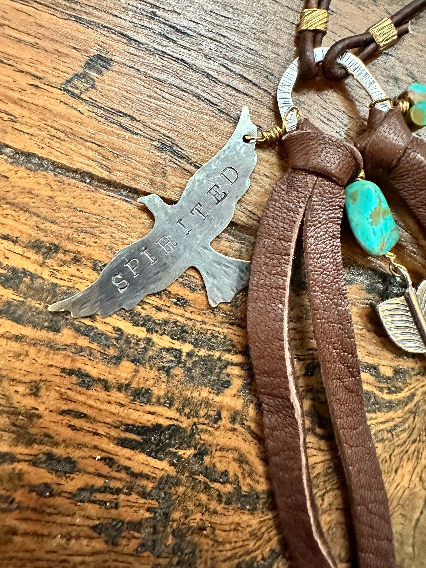 Silver bird charm with leather and turquoise beads.